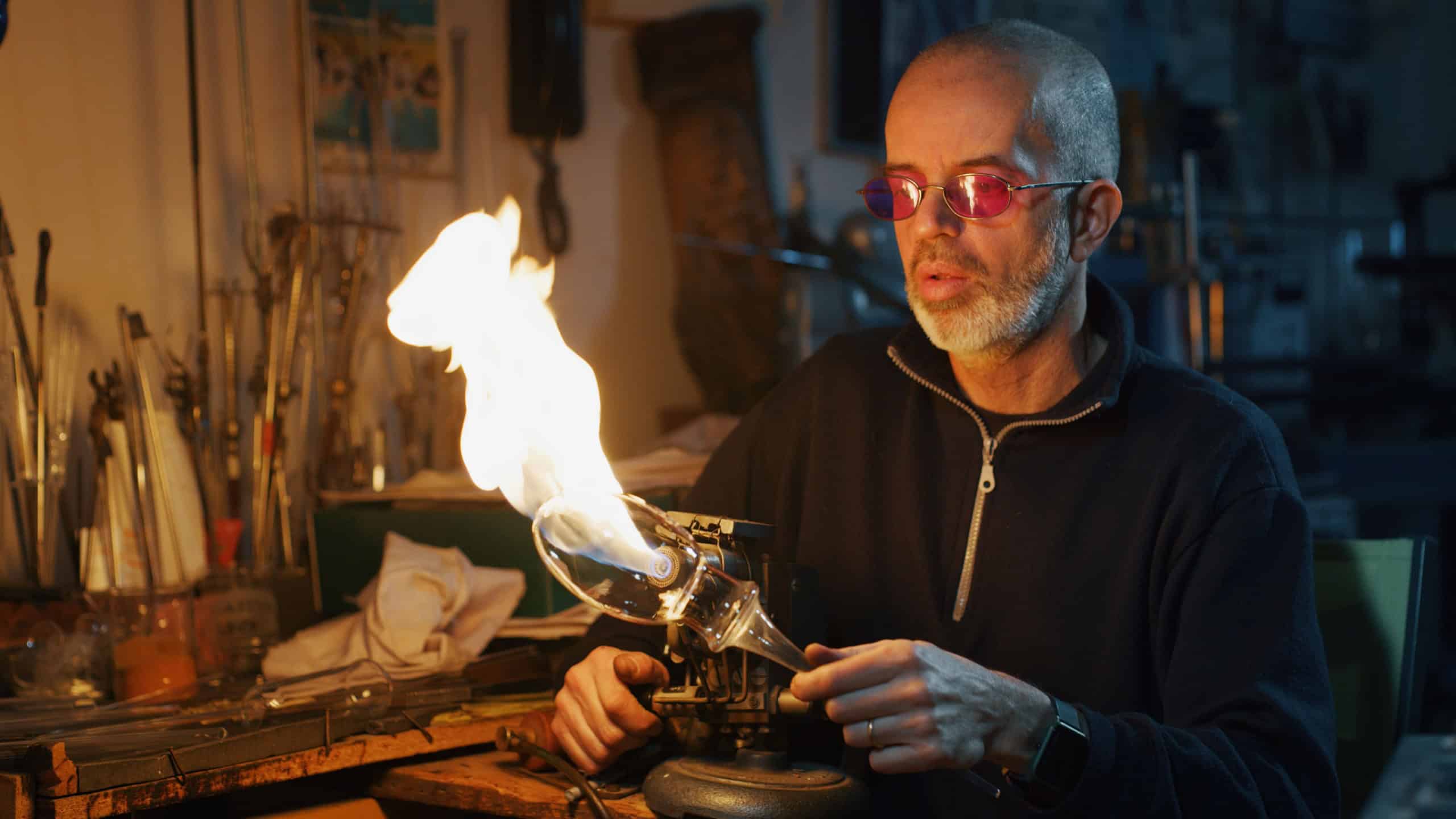 Close up macro of glass blower working with flame on a handmade wine glass from precious crystal in a workshop. Concept of handmade,high quality, artisan, made in Italy,glass blowing