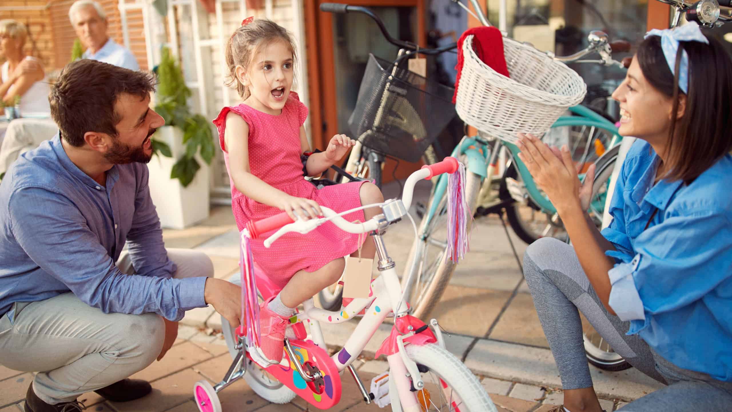 Young father buys happy daughter new bicycle in bike shop