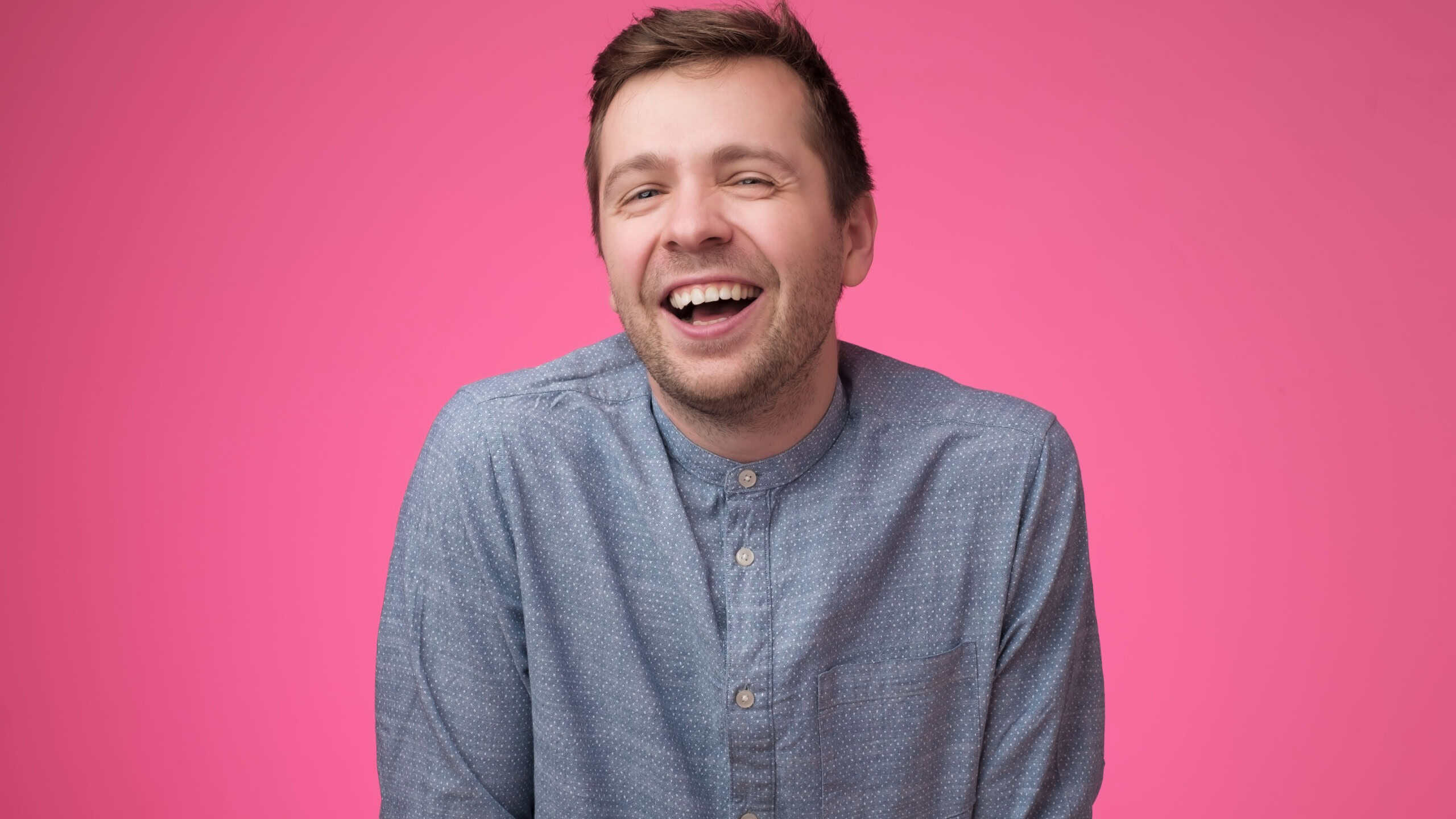 European young man laughing on funny joke. Studio shot. Positive facial human emotion