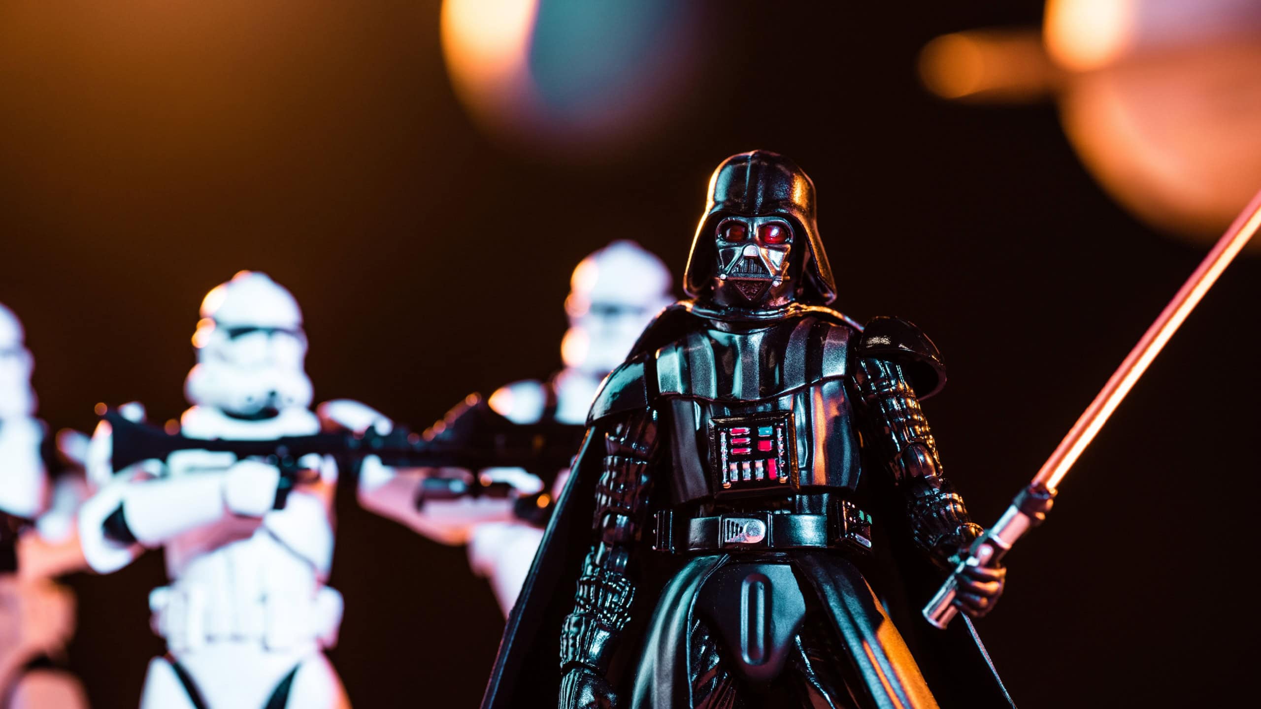 KYIV, UKRAINE - MAY 25, 2019: selective focus of Darth Vader with lightsaber and white imperial stormtroopers with guns on background
