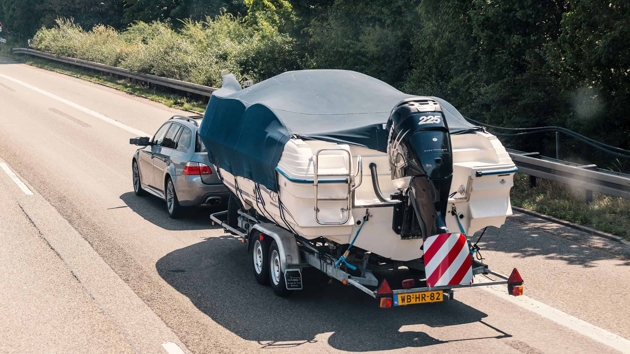 Car transporting a big boat on a highway