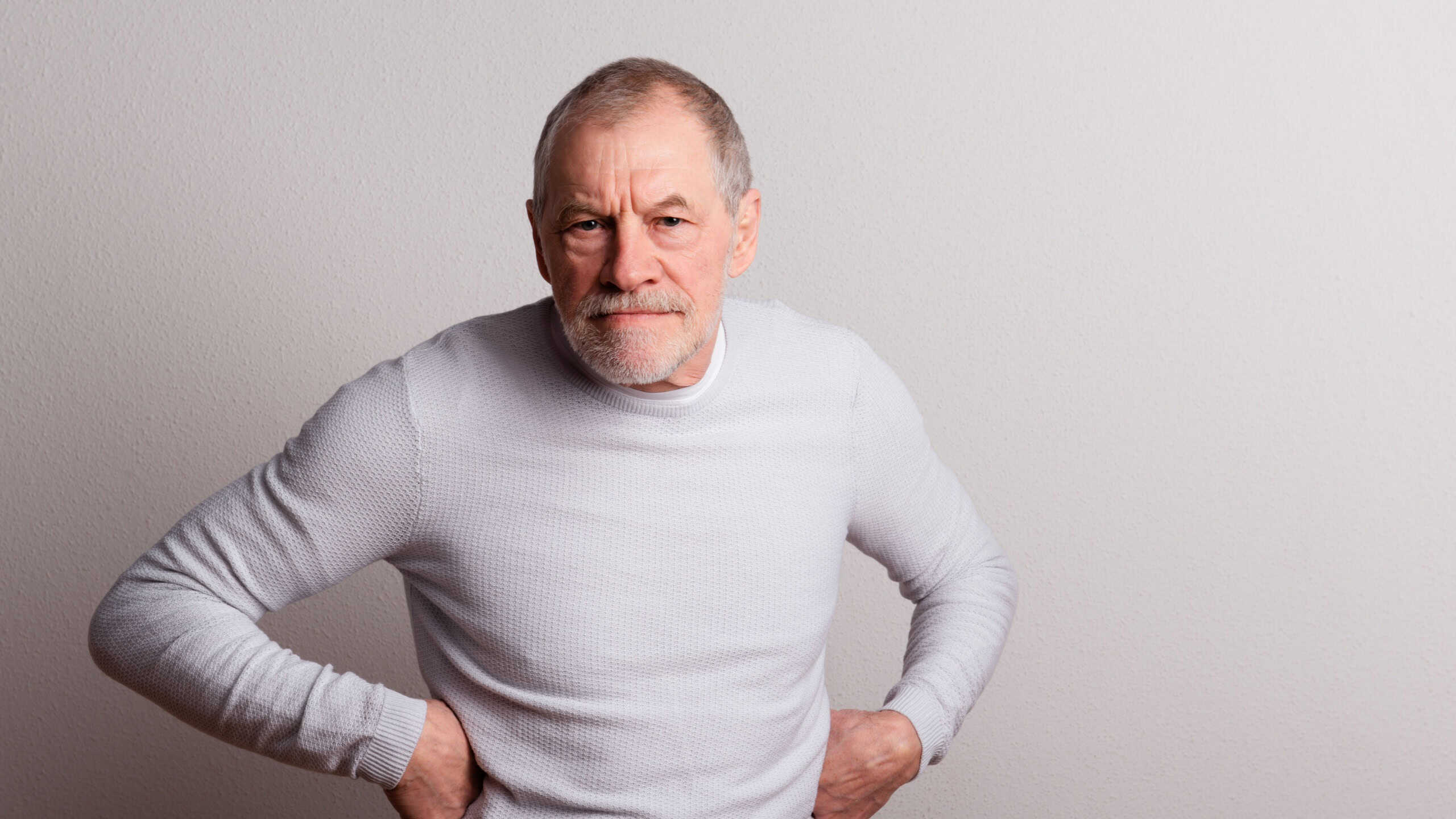 Portrait of an angry senior man with beard and mustache in a studio.