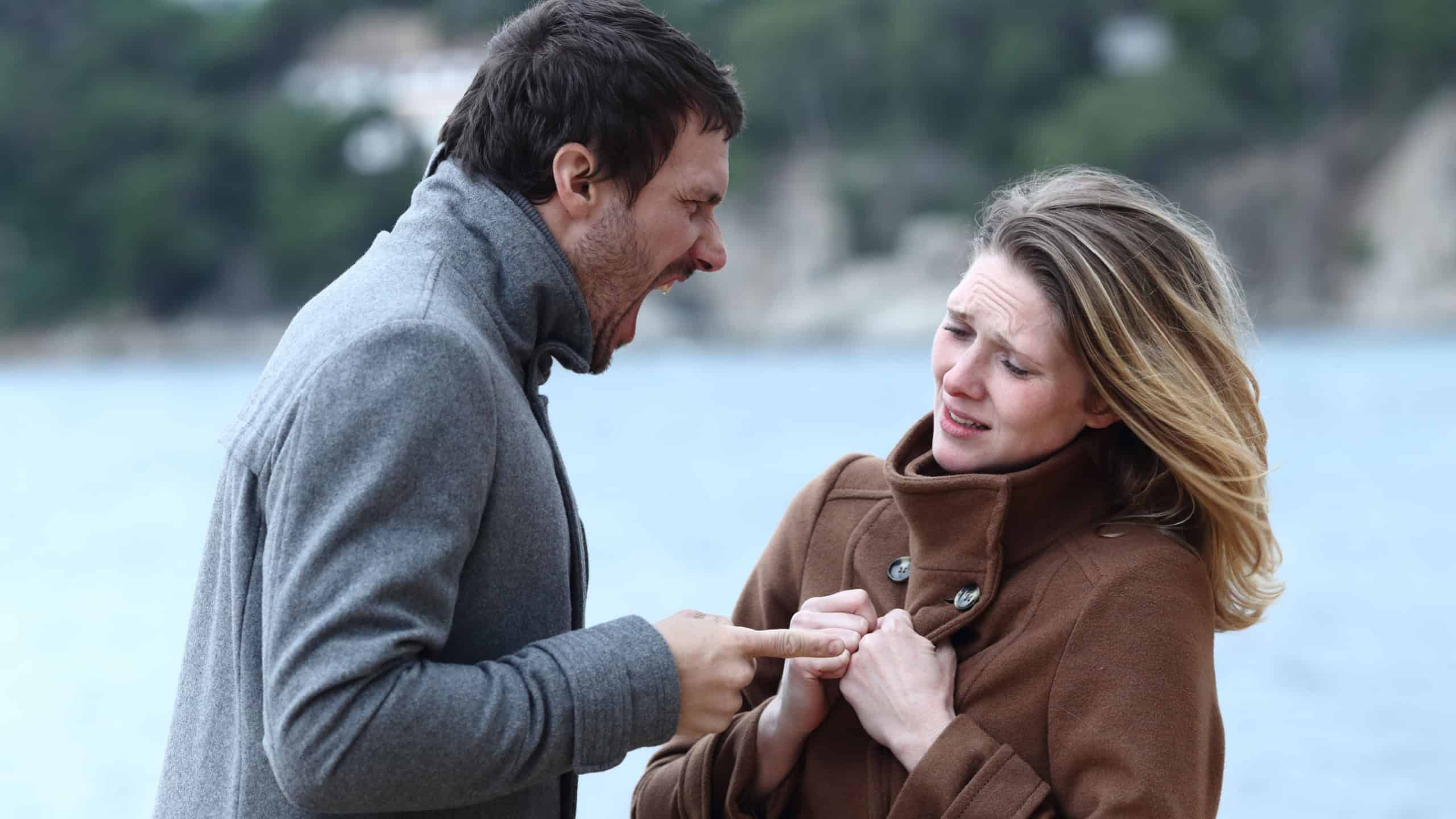 Angry man shouting to scared woman in winter on the beach