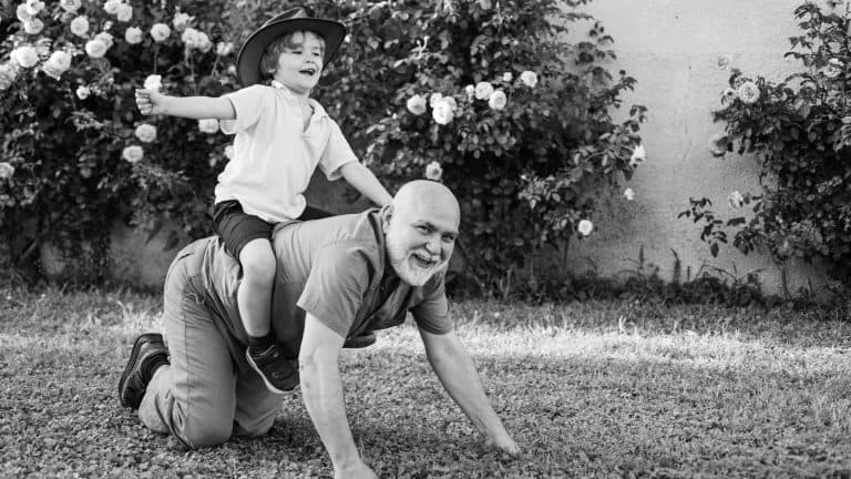 Two different generations ages: grandfather and grandson together. Grandfather with son in park. Happy family father and child on meadow with a kite in the summer on green grass