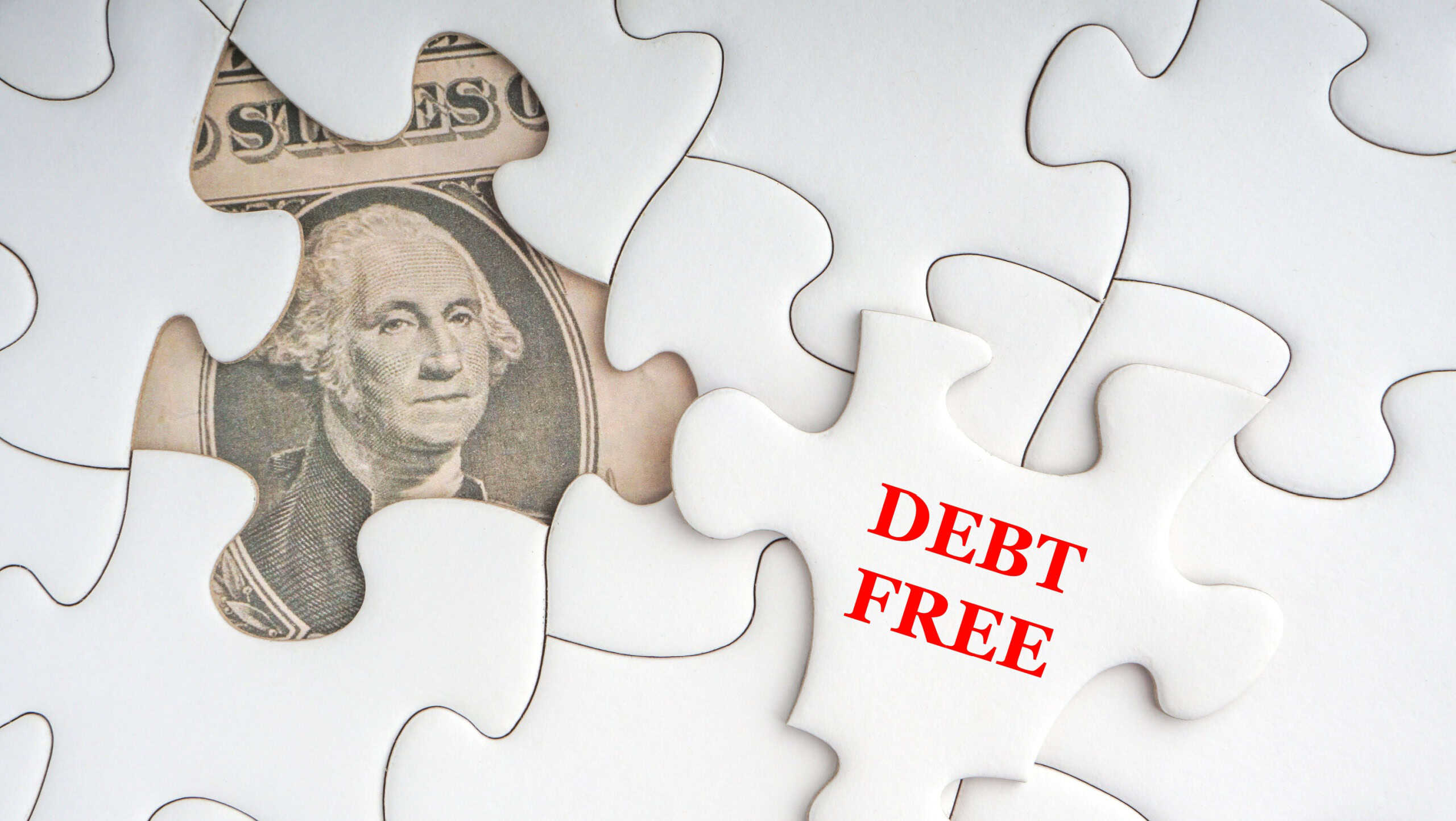DEBT FREE text with Dollar banknotes on white jigsaw puzzle. Business and copy space concept