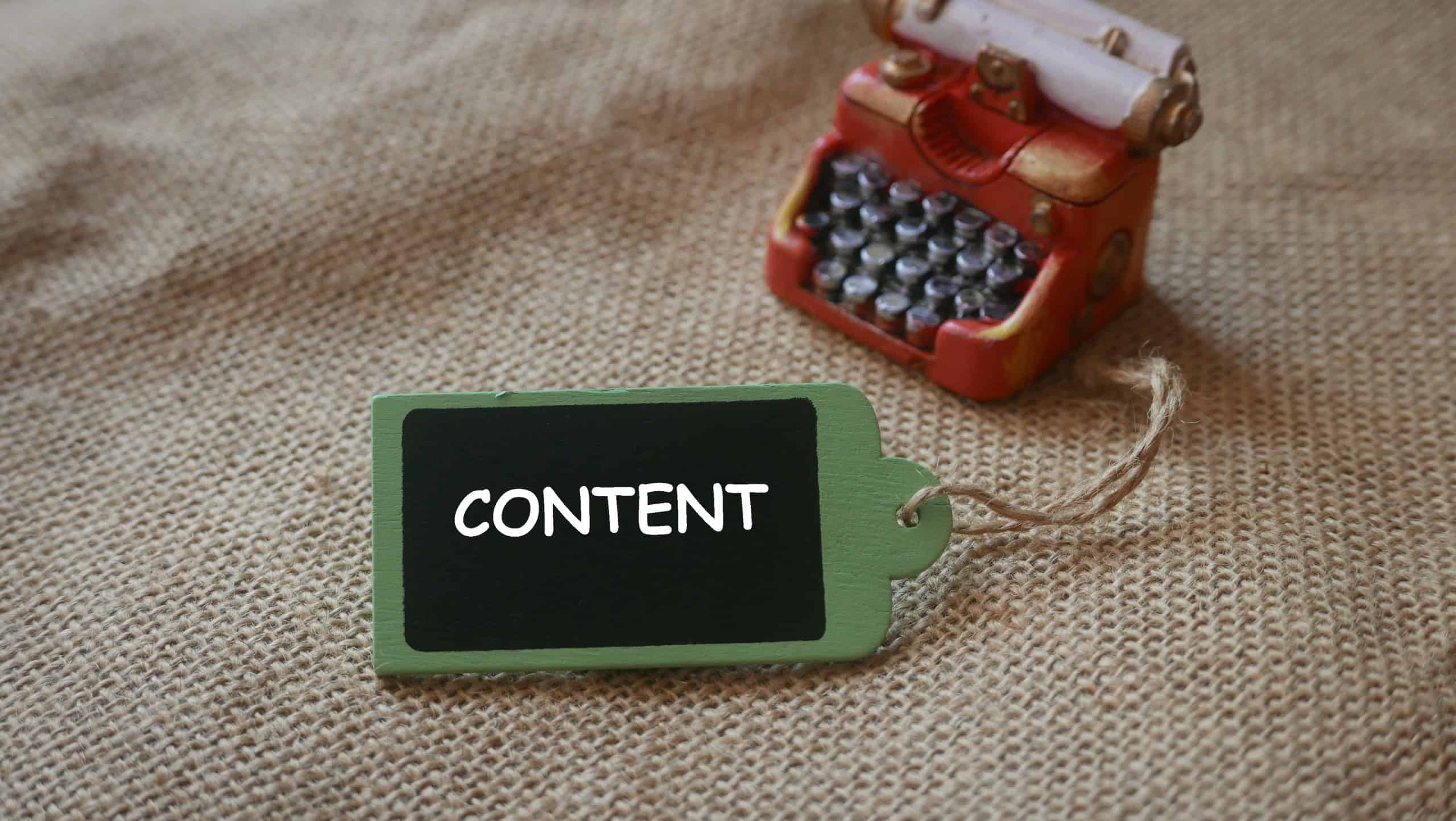 A red miniature of vintage typewriter with wooden tag written with CONTENT.