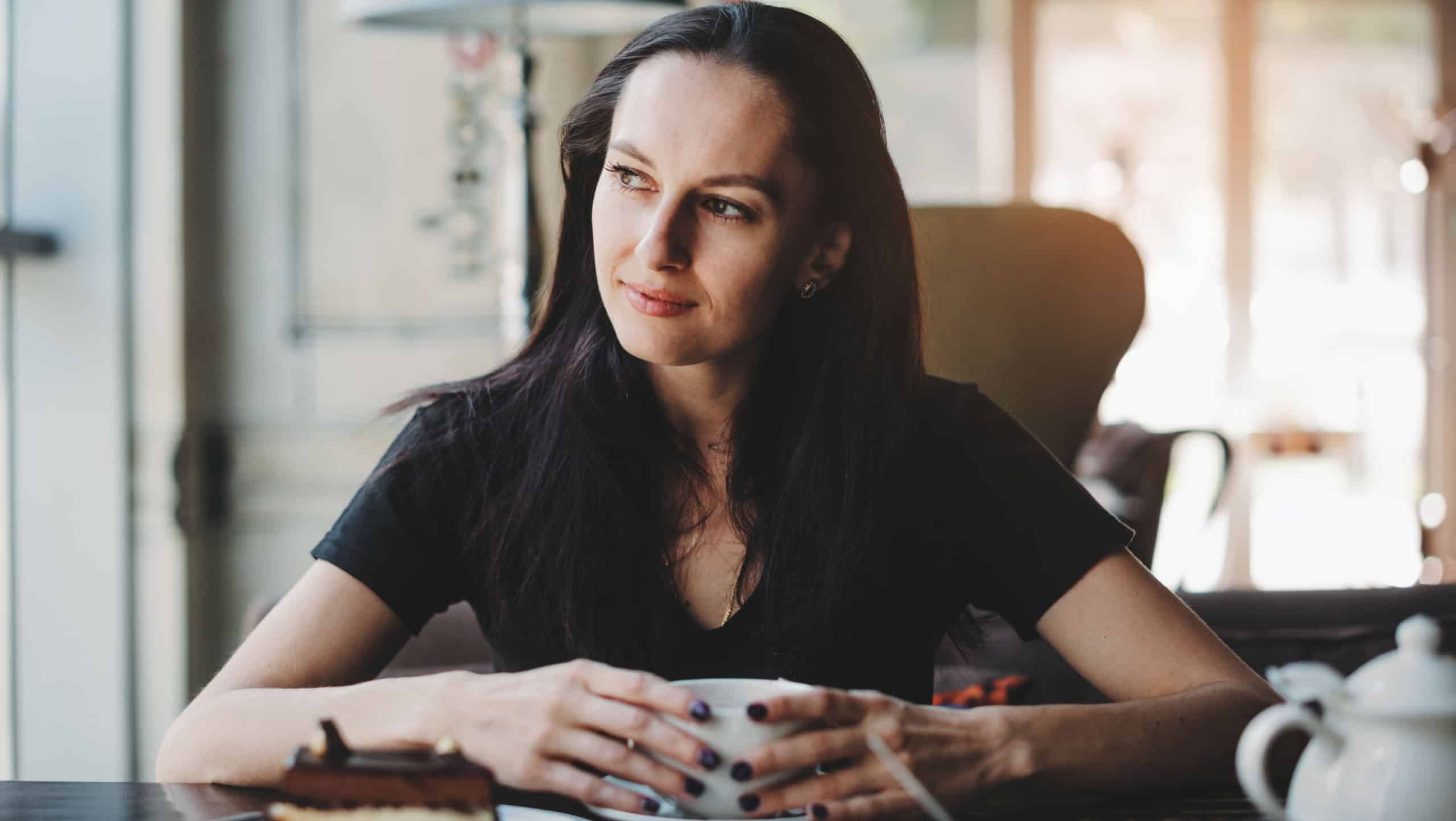Woman sitting in cafe with cup of coffee and smiling