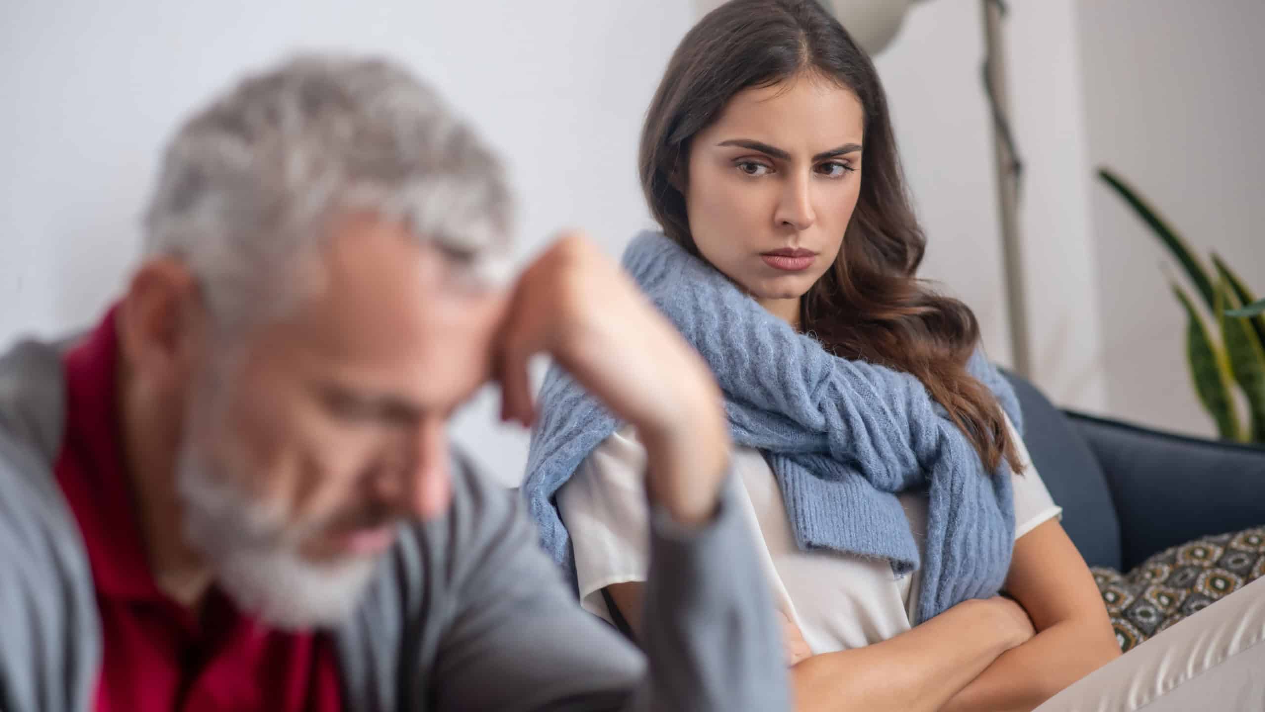 A woman looking angrily on her grey-haired husband