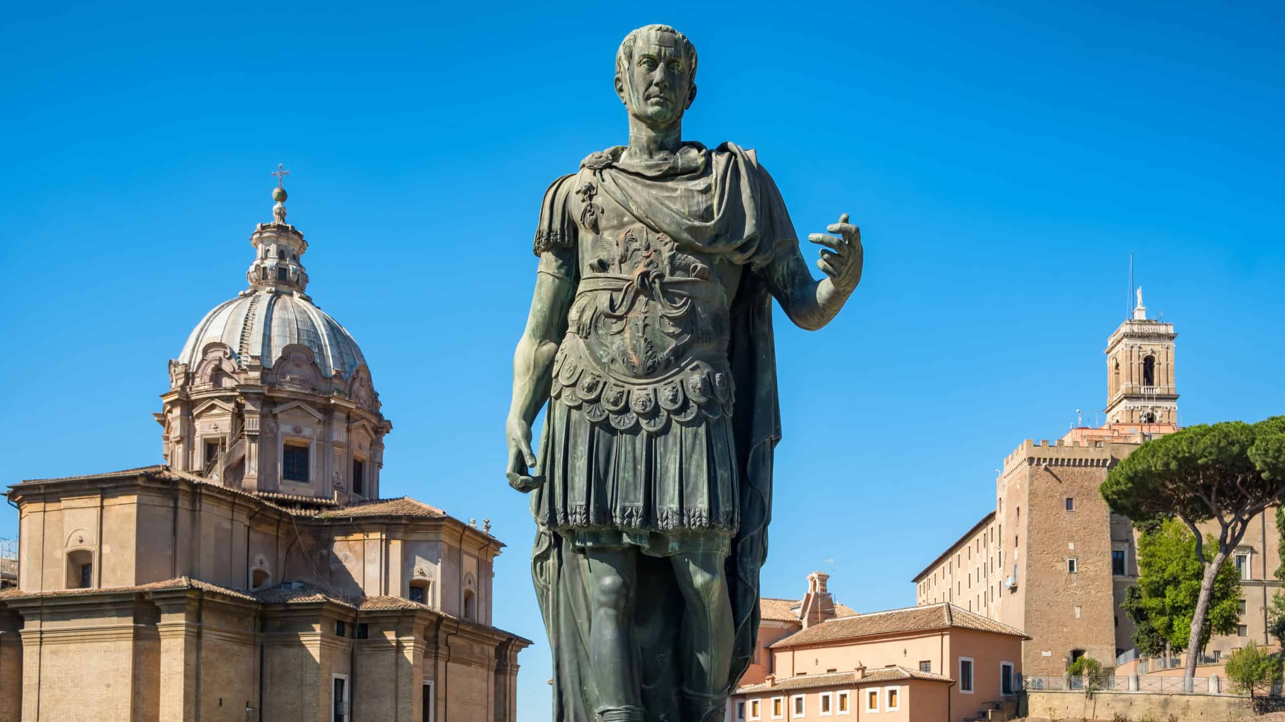 Ancient statue of Julius Caesar in Rome with Santi Luca e Martina church at background, Italy