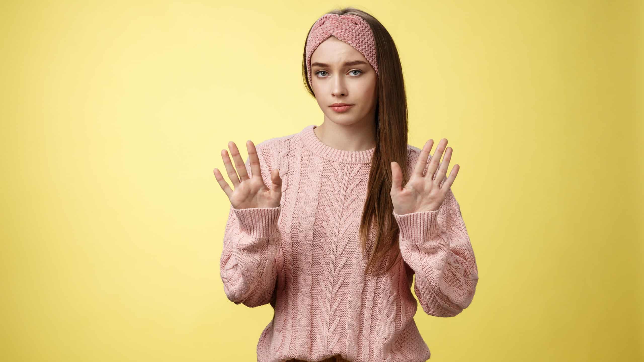 No thanks. Cute unamused picky young girl in knitted sweater, headband showing hold on, slow down, refusal gesture raising palms in rejection being reluctant unimpressed and indifferent to proposal
