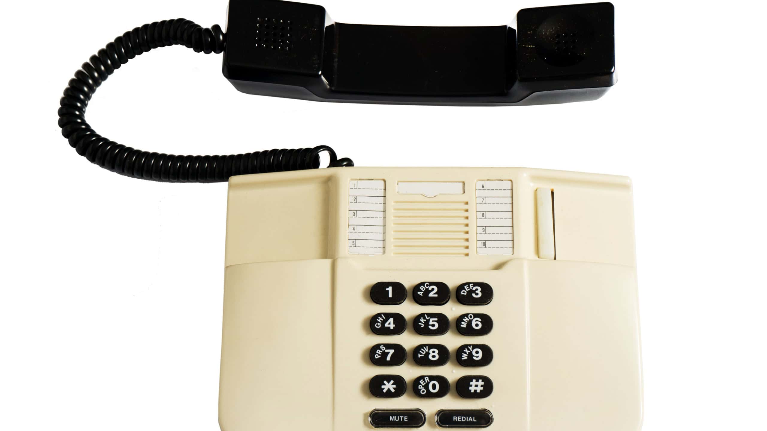 Landline corded push-button telephone isolated on white background. A beige plastic telephone with a receiver on a wire. Old model. Top view