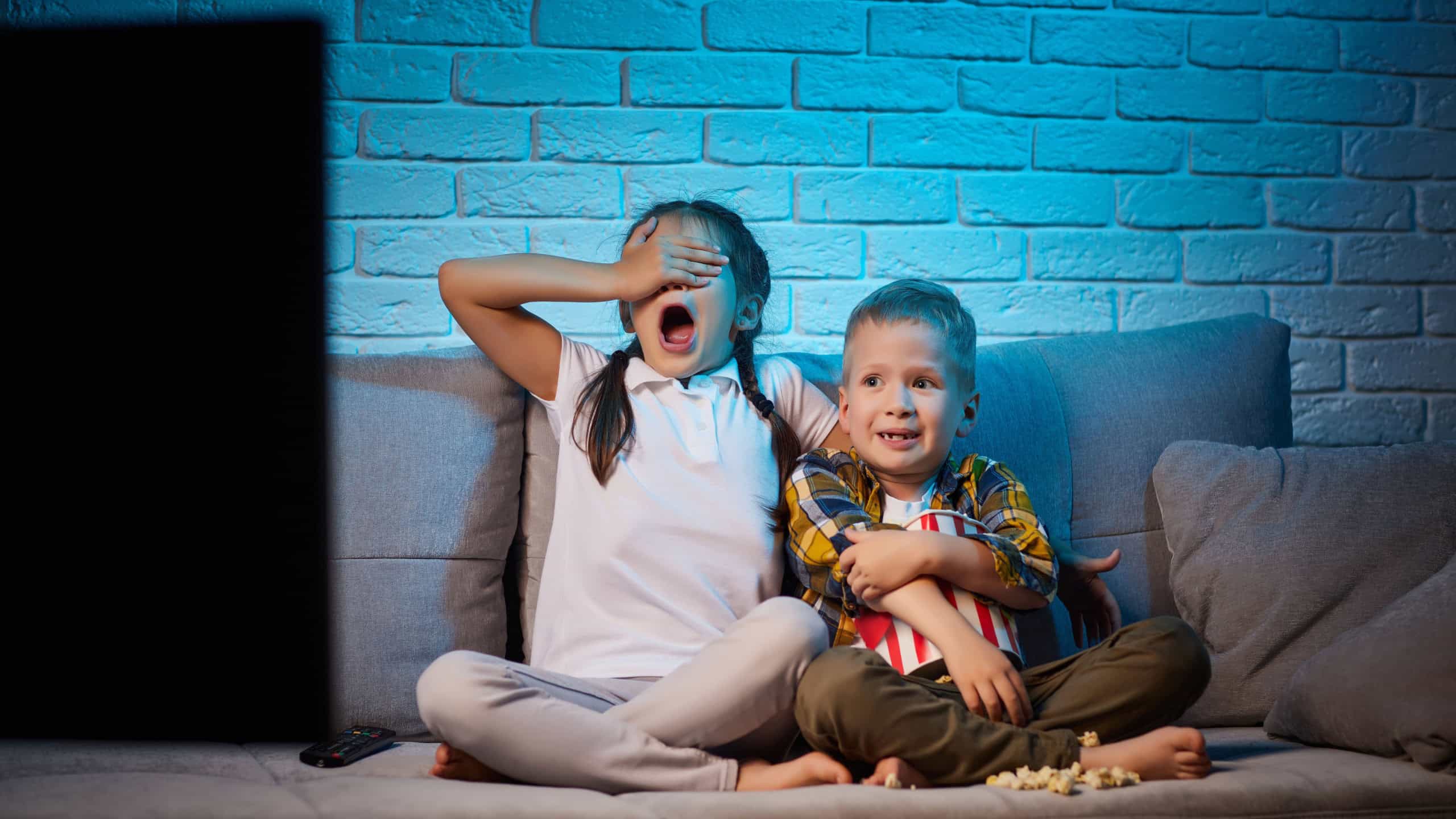 Two children with remote control watching TV
