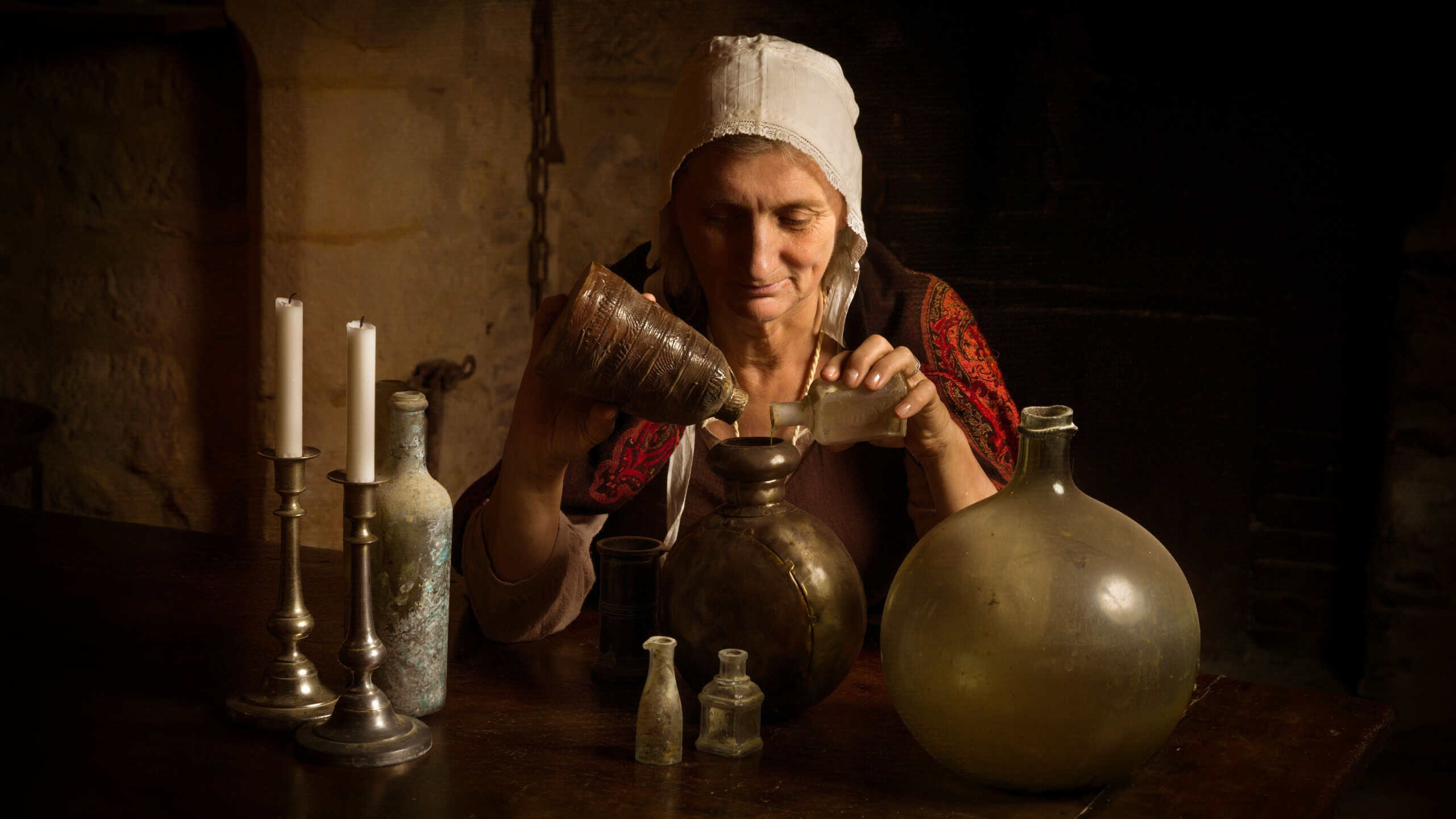 Woman in medieval outfit working as an alchemist or witch in the kitchen of a French medieval castle - with property release