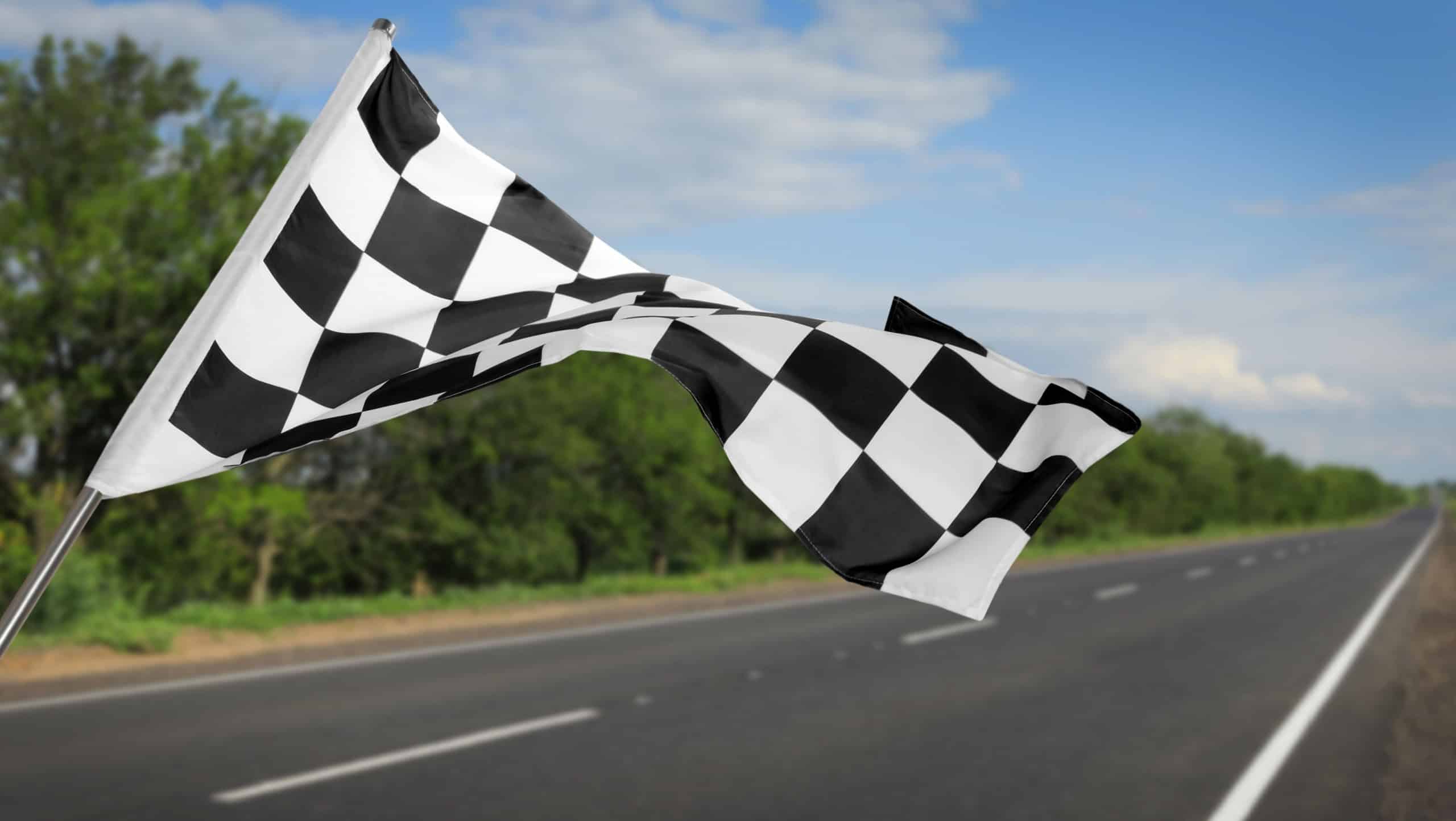 Checkered racing finish flag and asphalt road outdoors