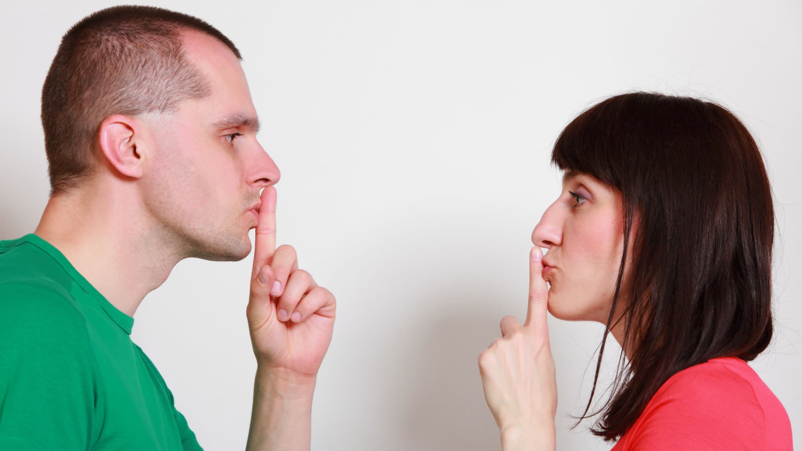 Woman and man showing hand silence sign, couple showing silence sign, holding index finger to lips