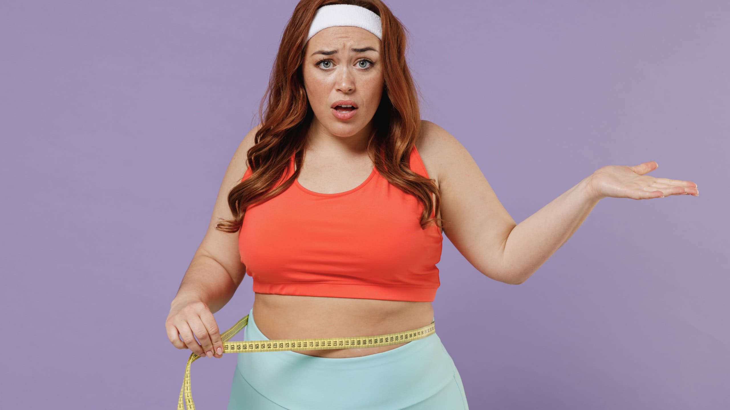 Young confused sad indignant chubby overweight plus size big fat fit woman in top hold measure tape waist spread hand warm up train isolated on purple color background home gym Workout sport concept.
