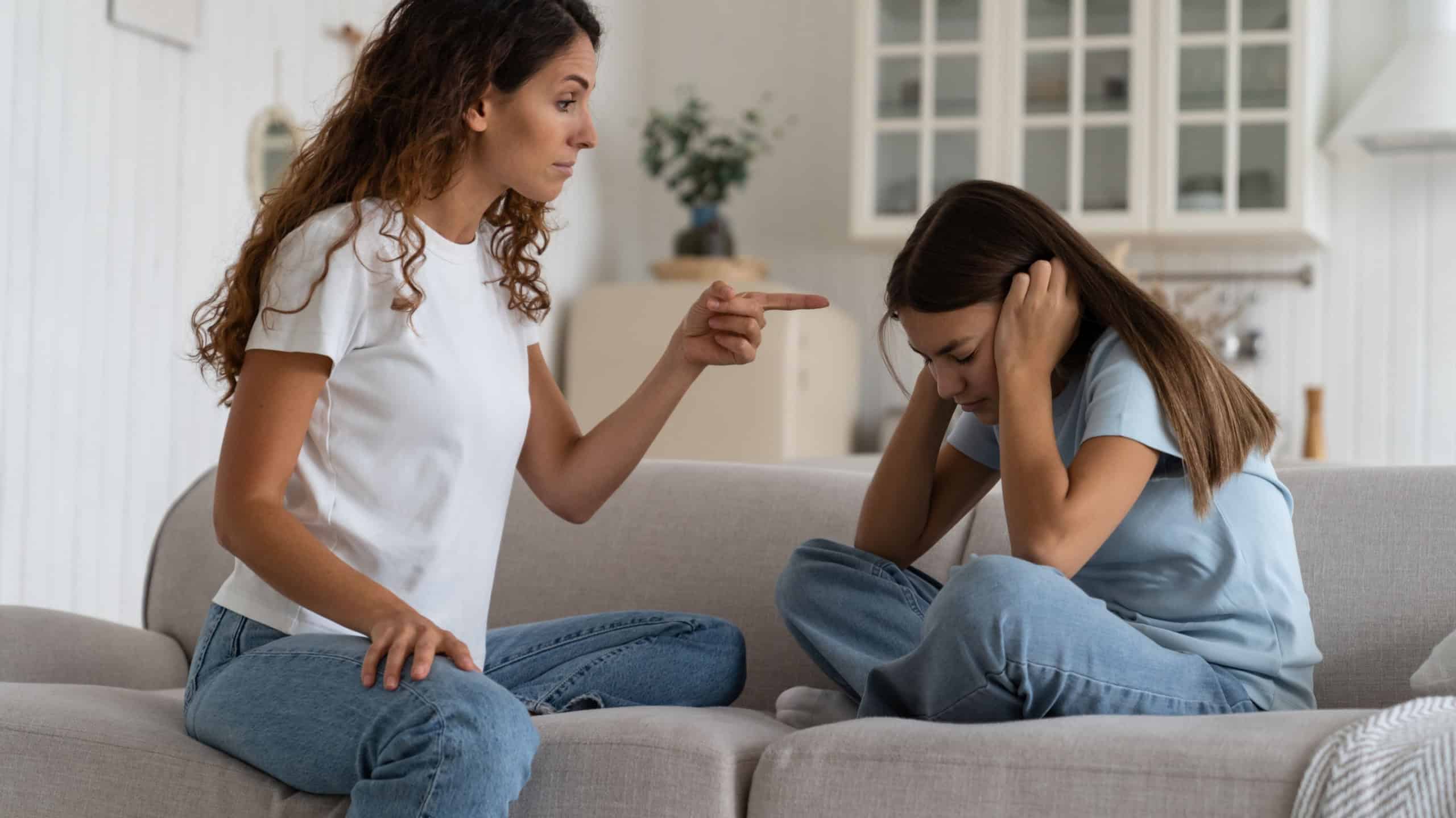 Upset unhappy teen girl daughter covering ears to not hear angry mother at home. Parent mom trying to discipline teenager kid who wont listen. Child abuse, parent-teen conflict concept