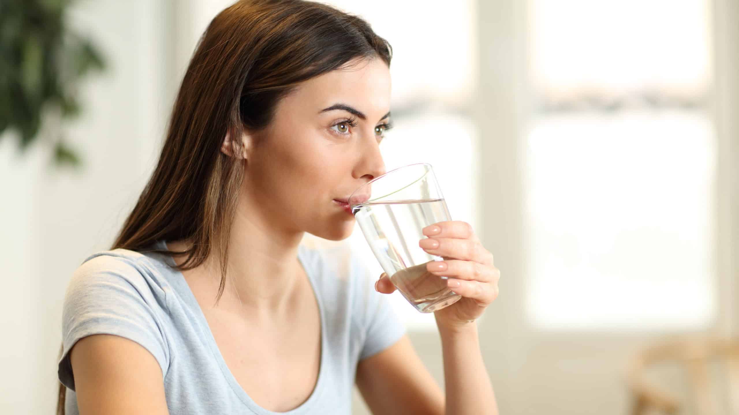 Woman drinking water from glass at home