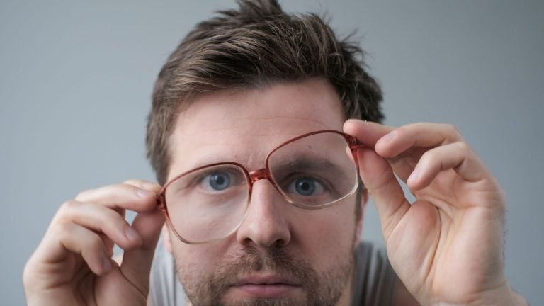 Surprised man in big glasses with WOW expression on gray backgound