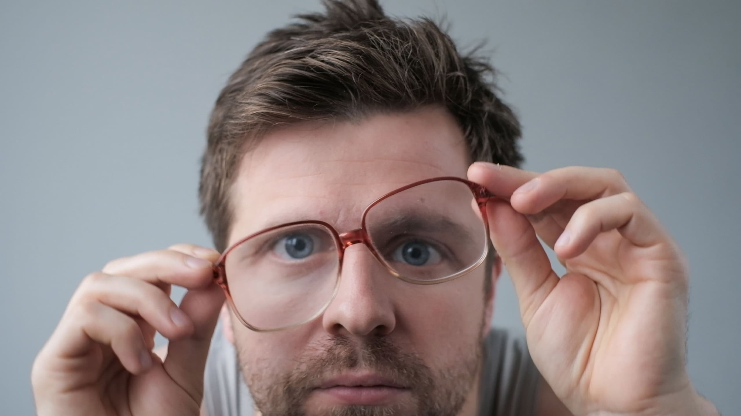 Surprised man in big glasses with WOW expression on gray backgound