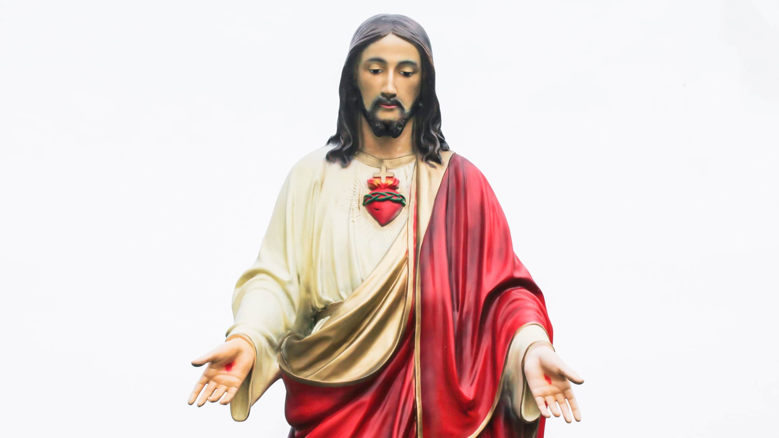 Jesus statue isolated on white. Open arms Jesus Christ. Catholic religion statue. God son Jesus in red robe.
