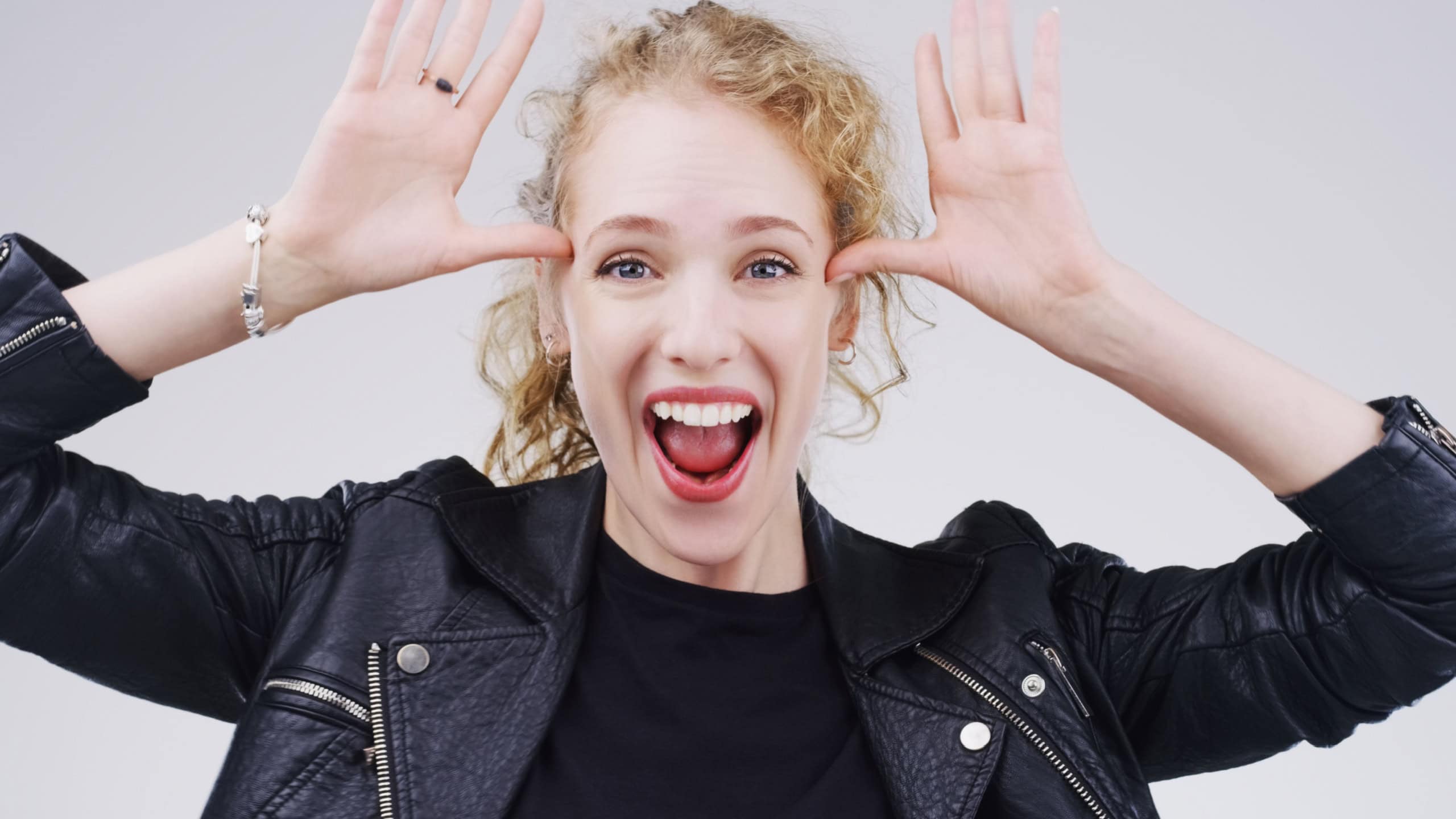 Woman, crazy and portrait with funny face in studio for comic, comedy and silly emoji by white background. Female person, goofy and hand on head for joke, good mood and facial expression on backdrop