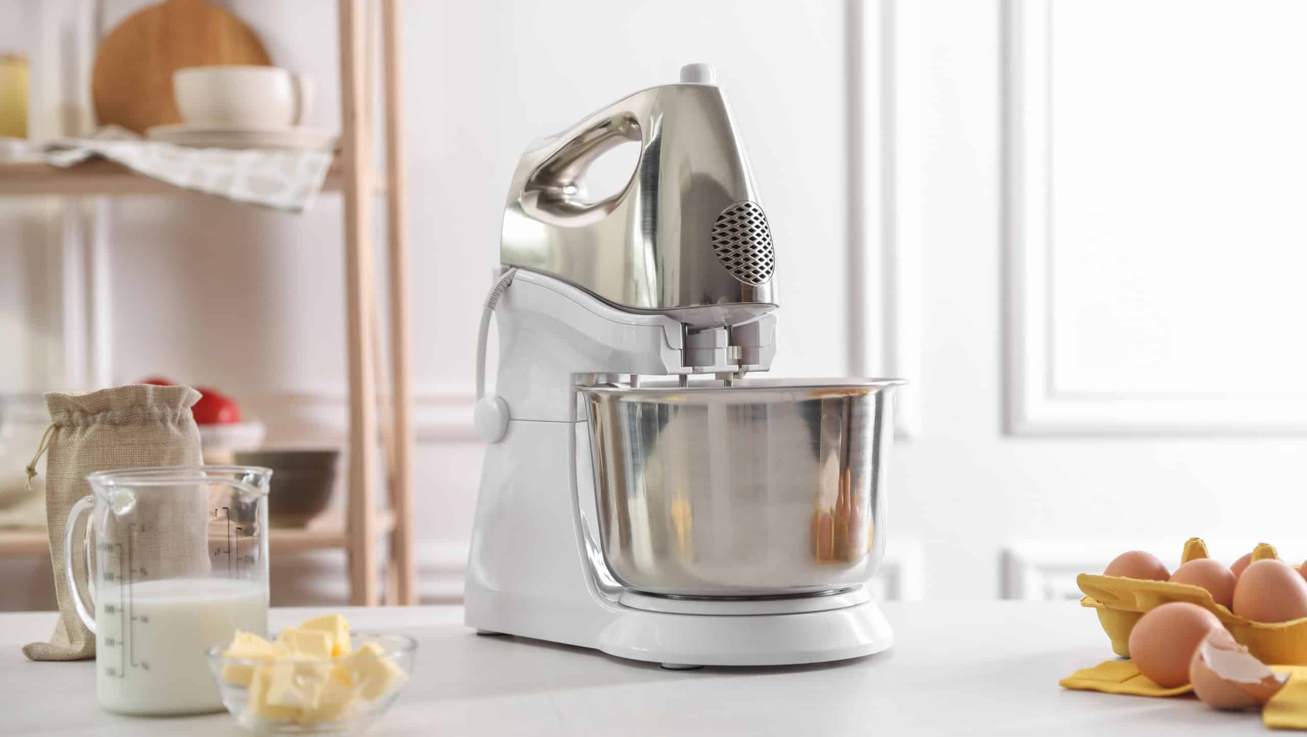 Modern stand mixer and ingredients for dough on white table indoors
