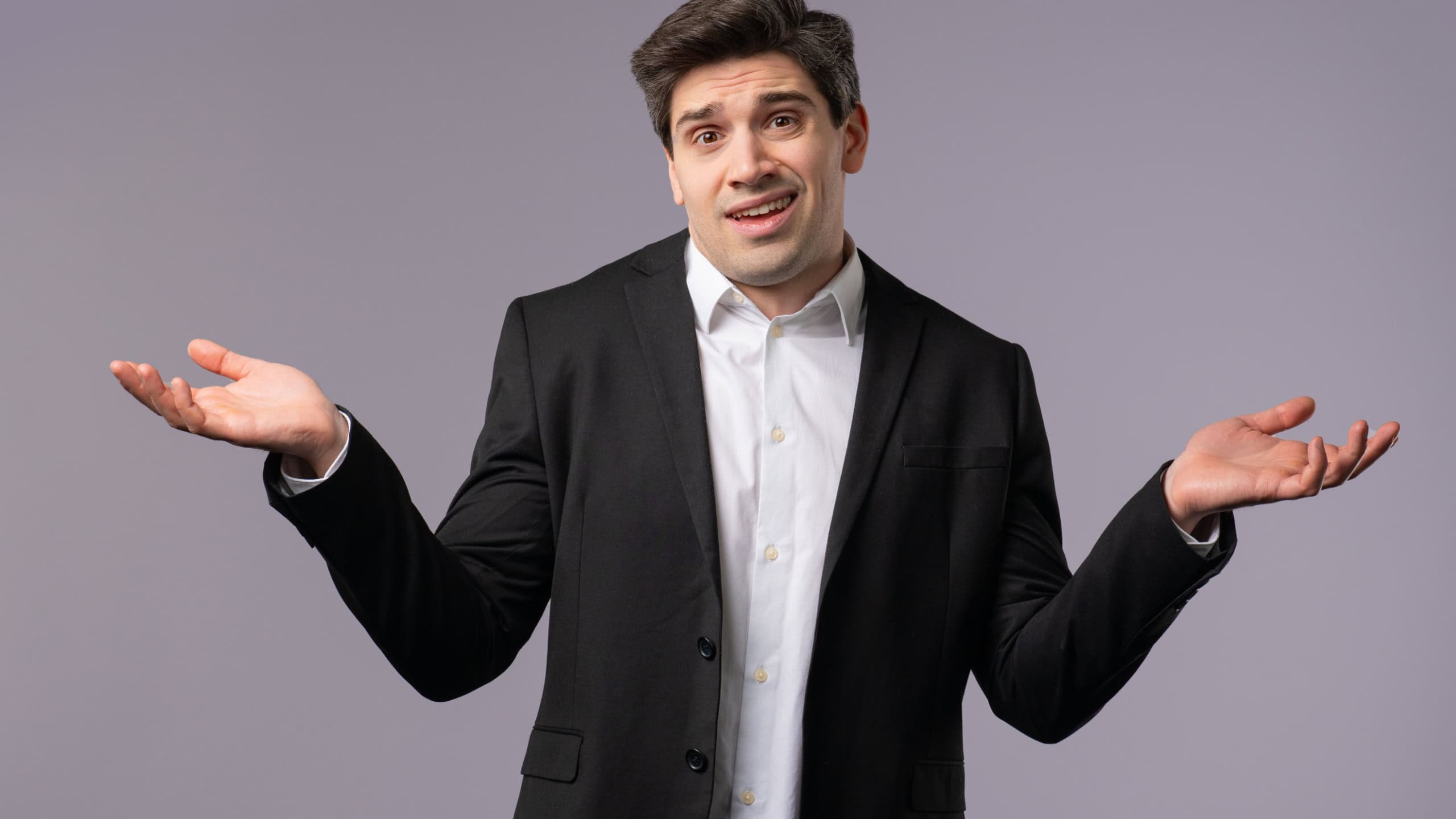 Confused 30s aged businessman in formal wear, shoulders up - can't help, makes gesture of I dont know. Difficult question, guilty reaction, puzzled man on grey background. High quality