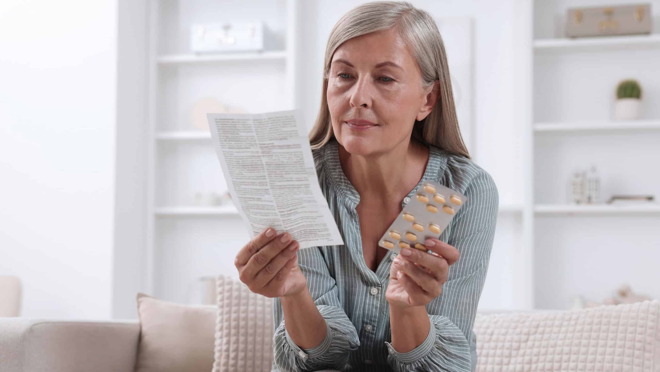Senior woman with pills reading medicine instruction at home