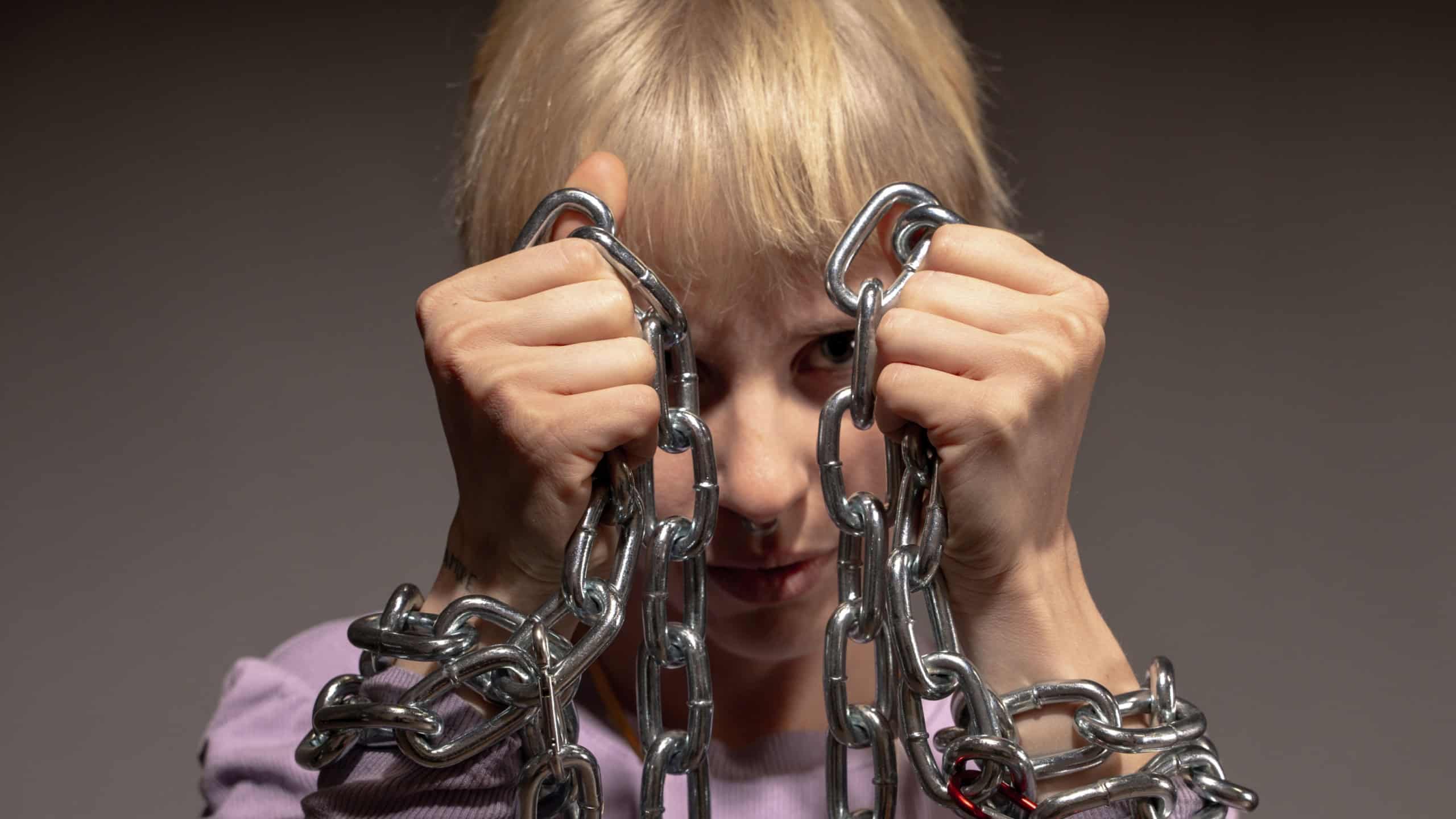 Young person holding metal chains with determined expression - Freedom and breaking barriers concept portrait