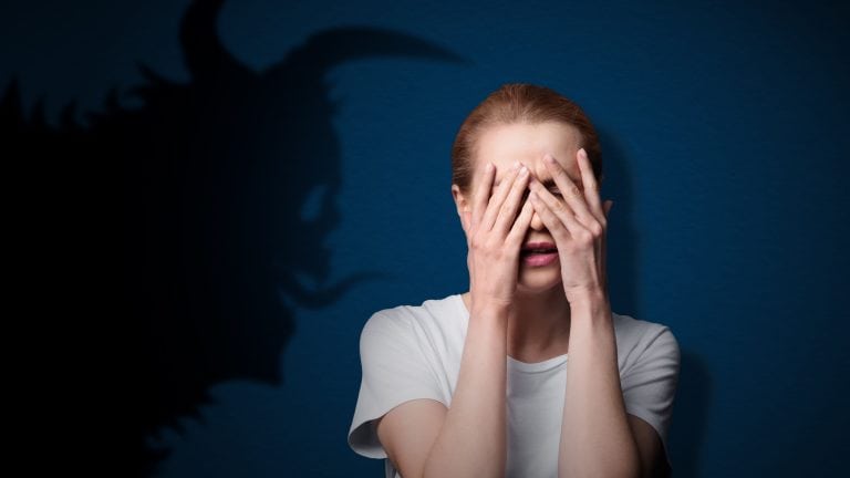 Woman scared by monster. Creepy shadow on blue wall