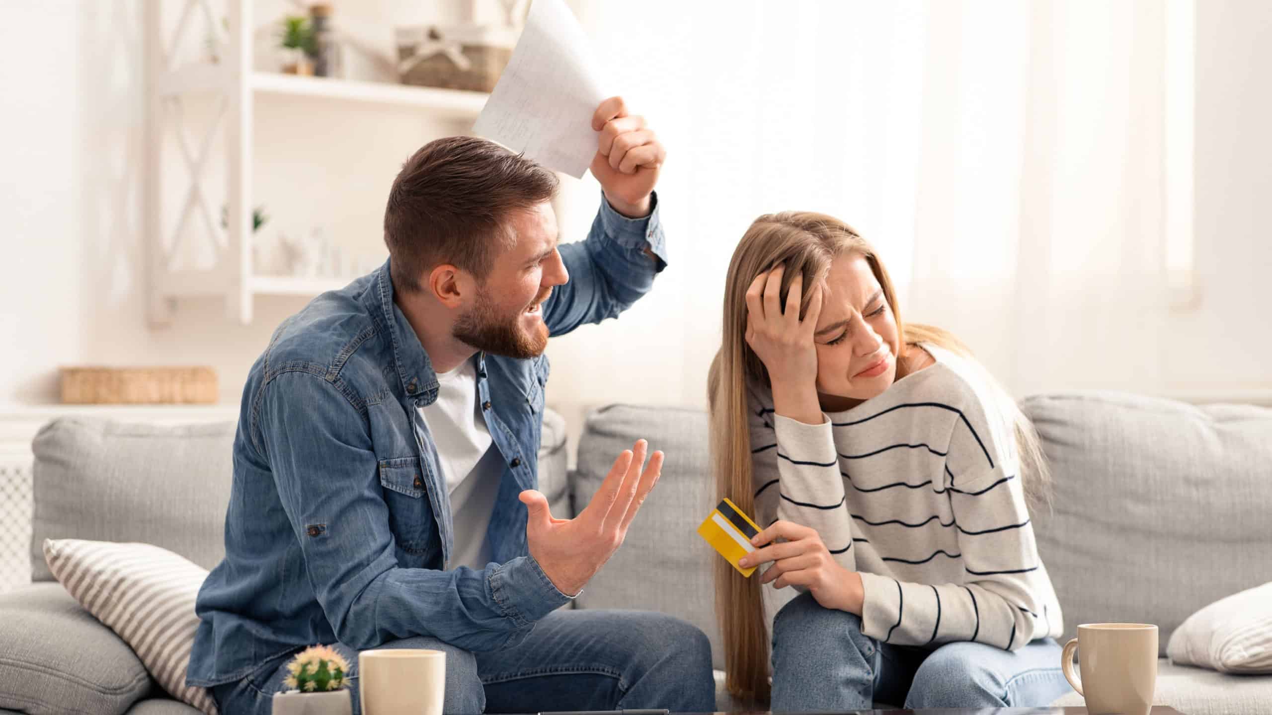 Financial crisis in family. Angry husband shouting at his guilty wife with huge credit card bills at home