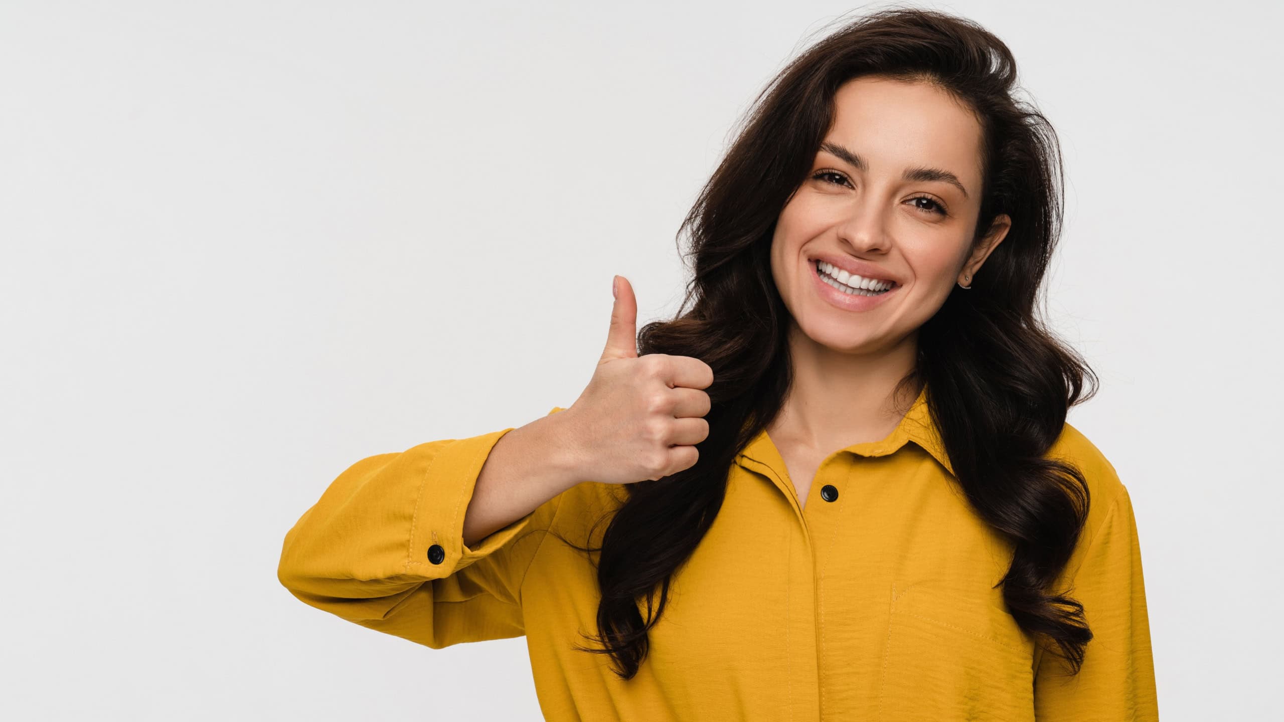 Portrait of happy young woman with thumb up sign gesture isolated on white background in casual clothes. Smiling lady recommend service, give sincere recommendation, advice good or sale offer