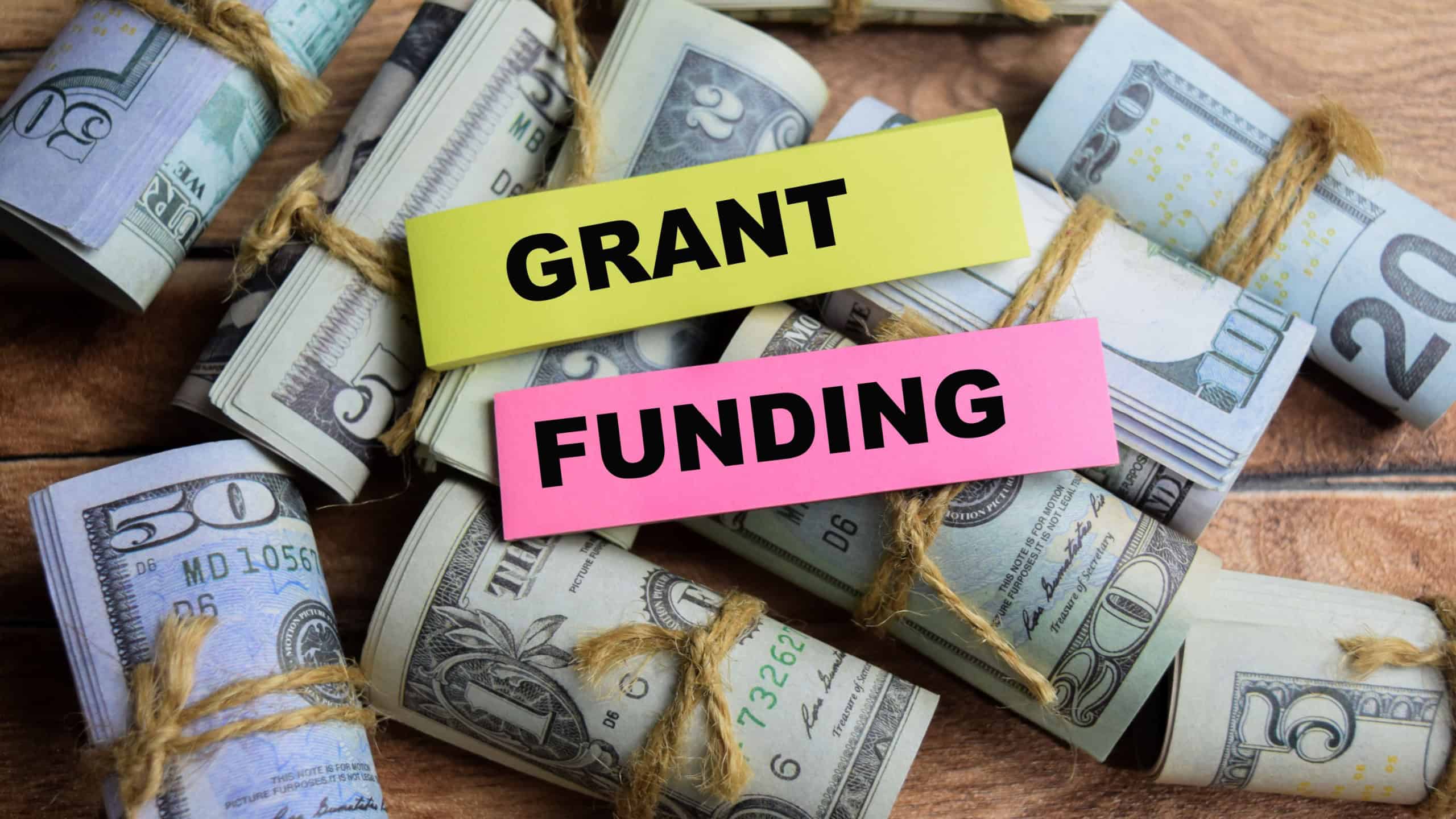 Concept Grant Funding on sticky notes on a wooden table with dollar bills