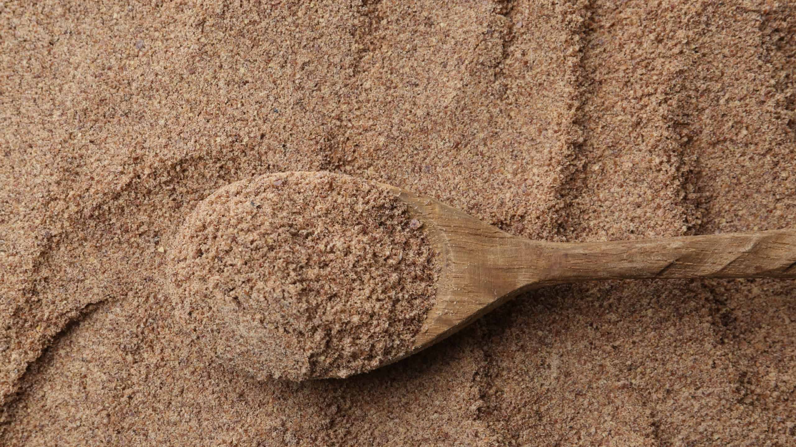 Superfood product. Flaxseed powder and spoon as background, closeup