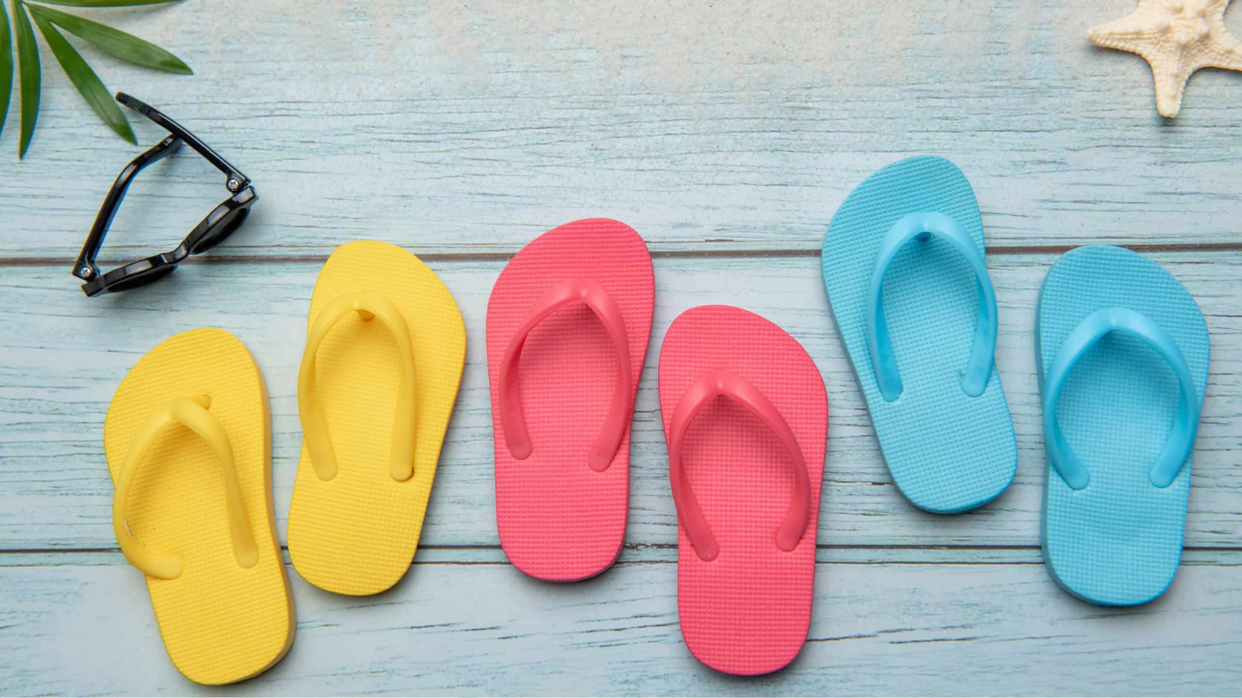 Vibrant flip flops and sunglasses arranged on a weathered boardwalk evoke a sense of carefree summer relaxation