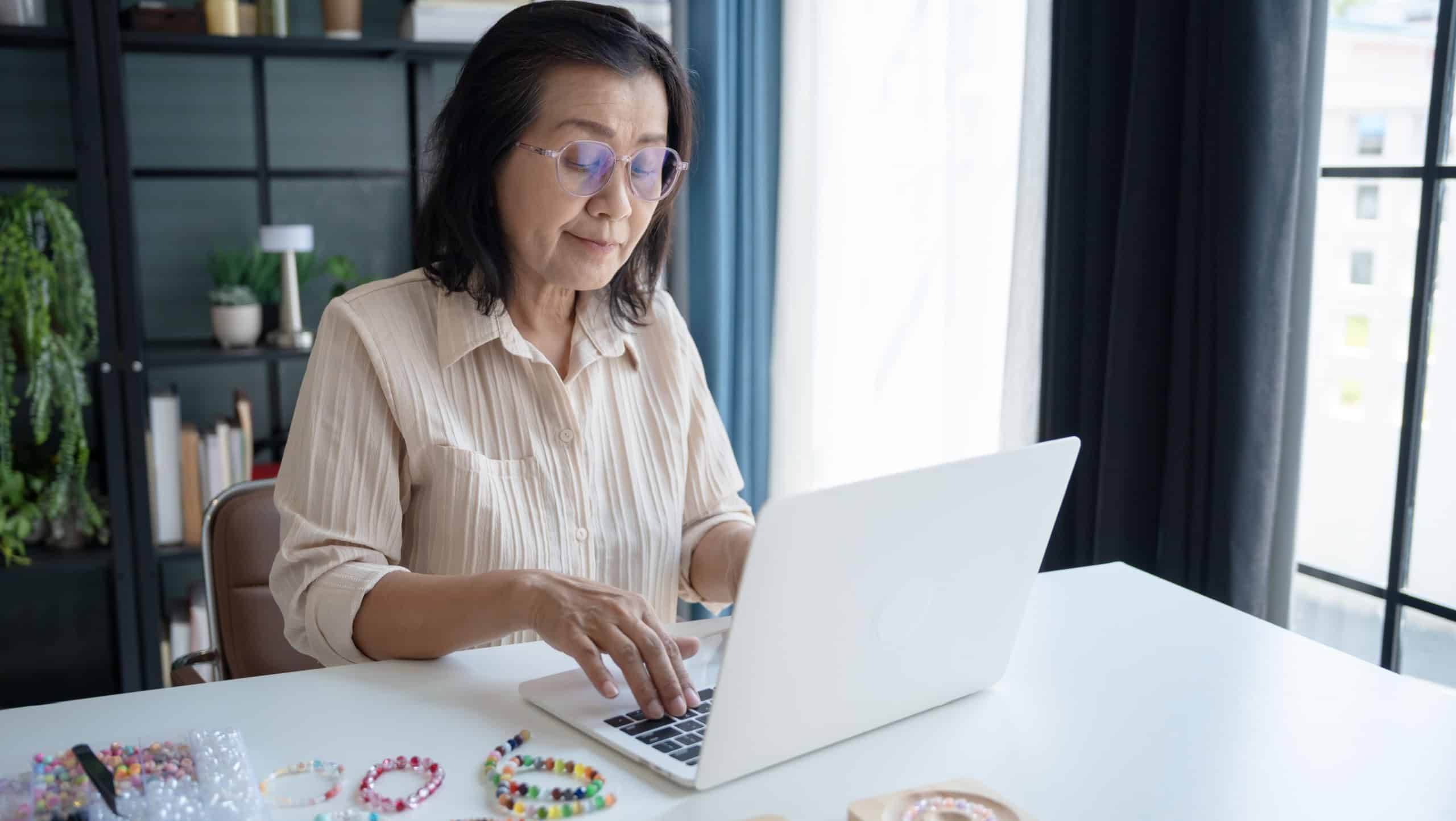 Mature asian woman business laptop E-commerce entrepreneurship owner preparing jewellery accessories handcraft