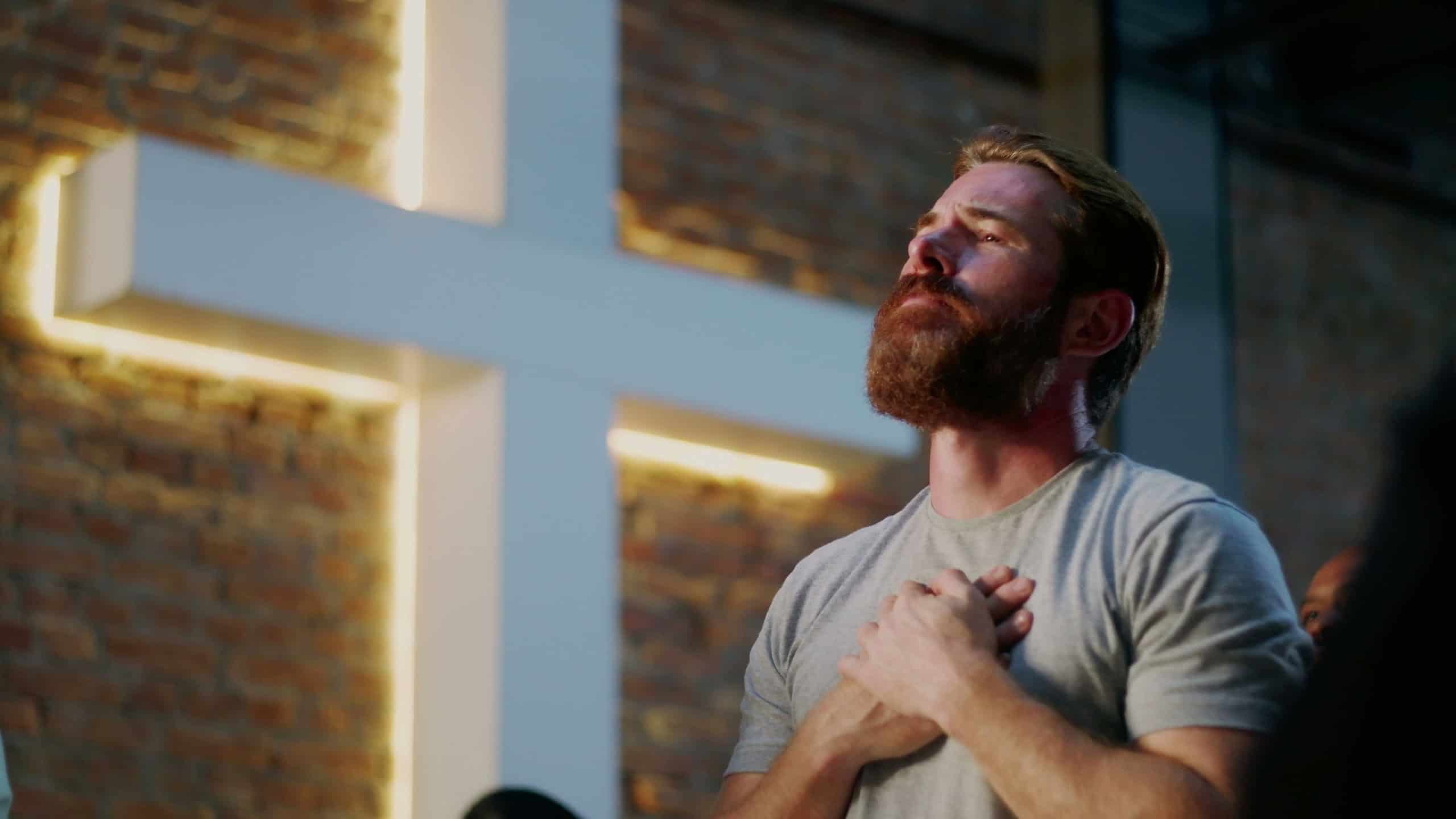 Man with hands clasped over heart in deep prayer, emotional connection, Christian faith
