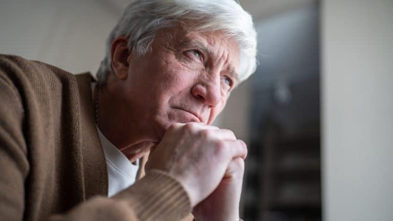 Older man sitting alone in emotional burden mental fatigue and deep depression. Elderly male loneliness, silent suffering in old age, psychological weight of sick, empty stare in later years