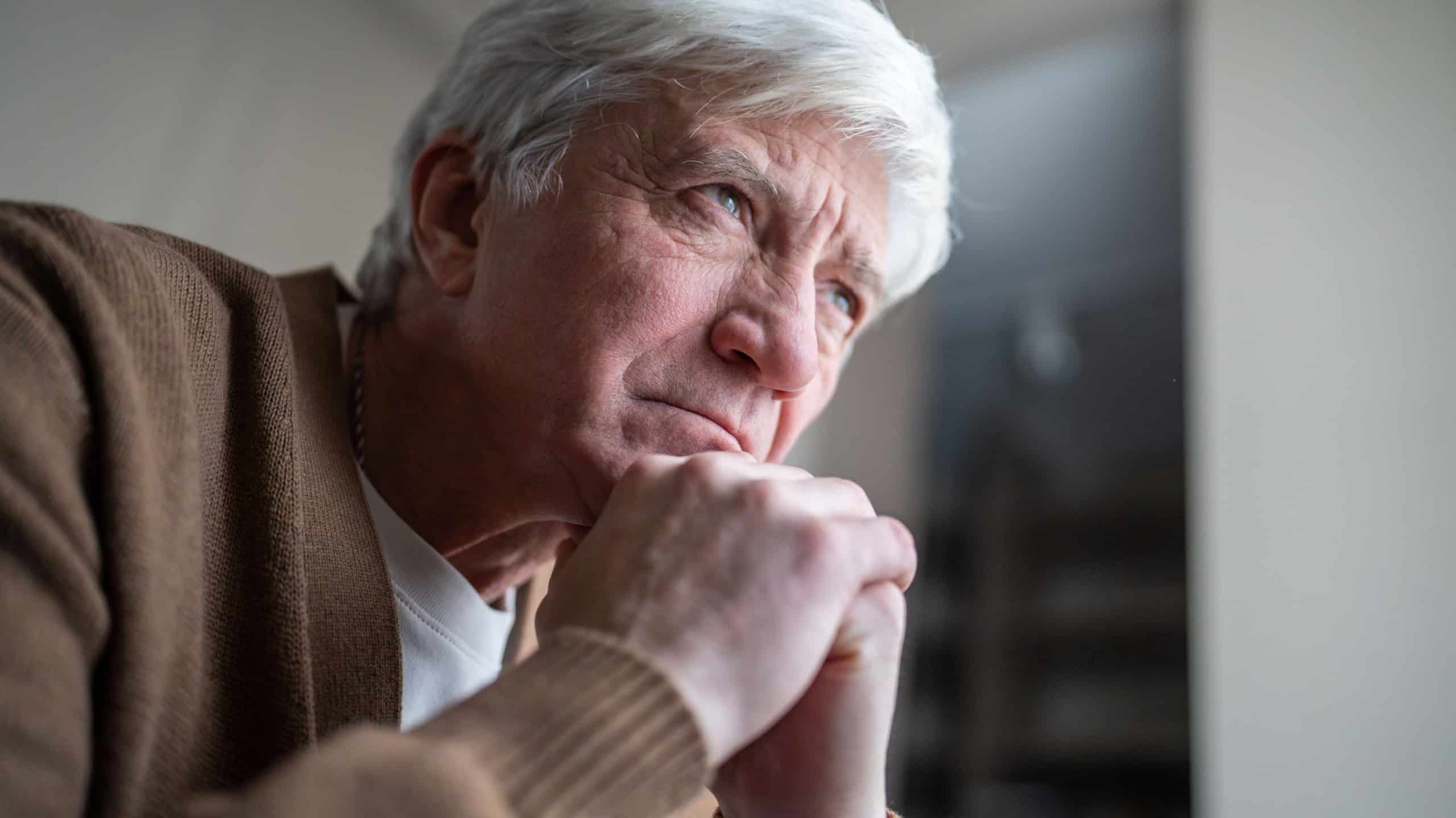 Older man sitting alone in emotional burden mental fatigue and deep depression. Elderly male loneliness, silent suffering in old age, psychological weight of sick, empty stare in later years
