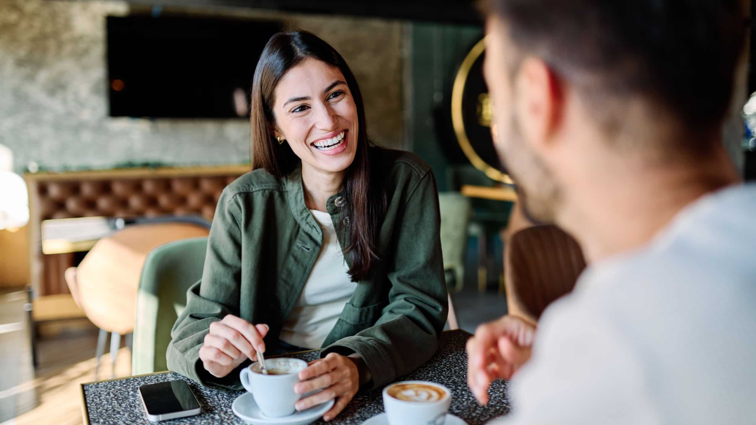 Young couple enjoying conversation and coffee together at an urban cafe table