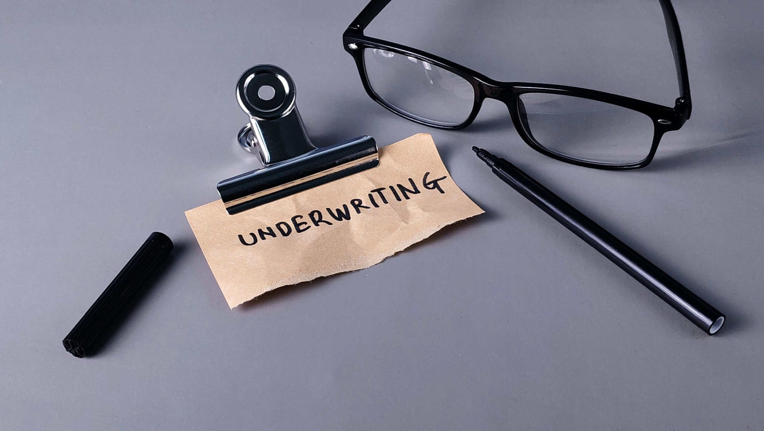 Underwriting Concept Note with Glasses, Pen, and Clip: Risk Assessment and Financial Approval