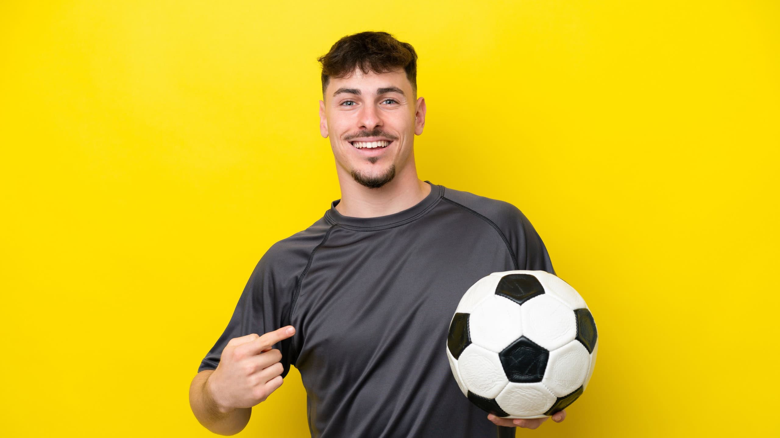 Young football player man isolated on yellow background with surprise facial expression