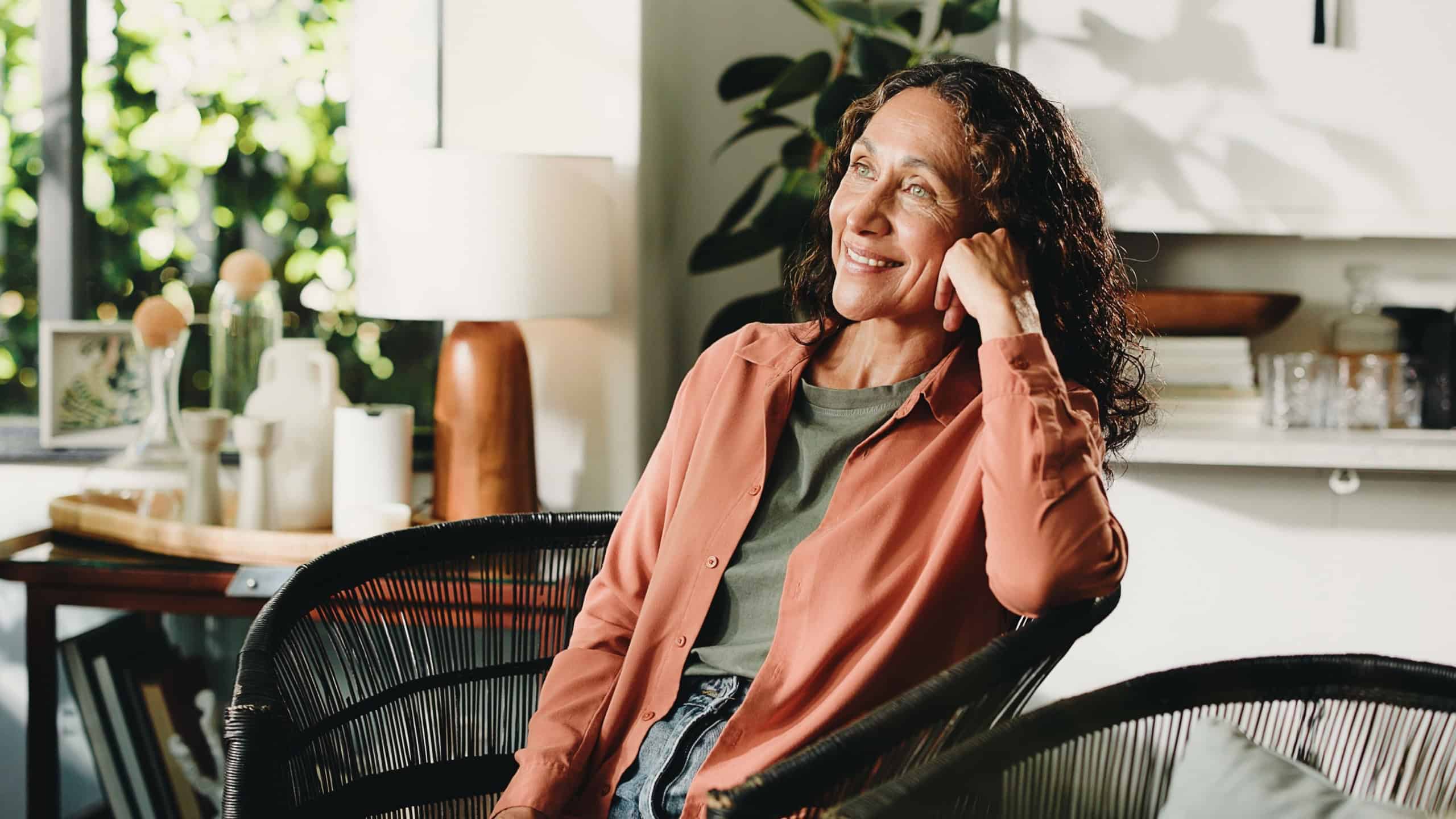 House, thinking and woman with smile, relax and reflection with weekend break. Retirement, comfort and mature person with contemplation and decision with moment, remember and memory with nostalgia