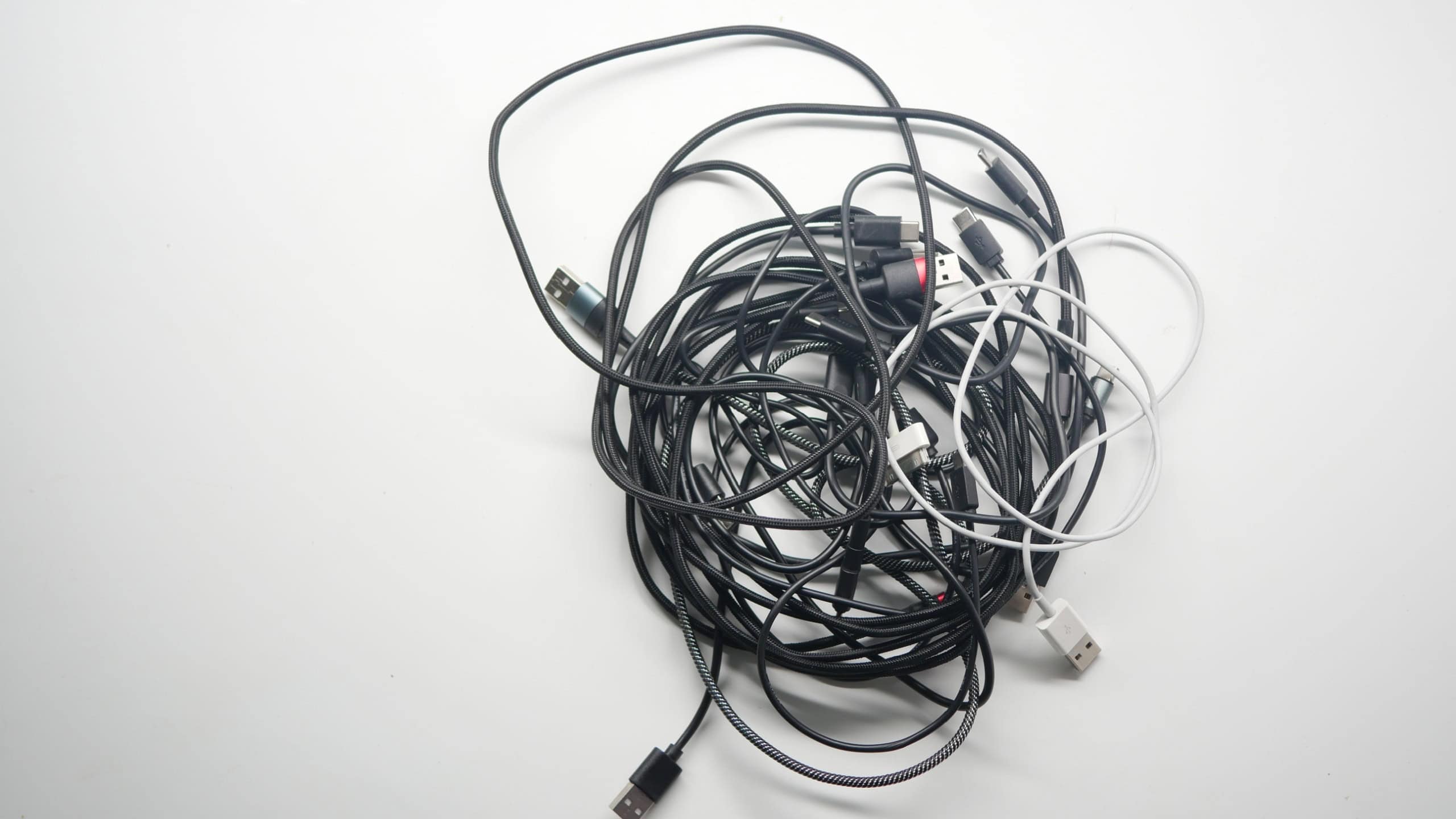 Multiple tangled charging cables on a white background