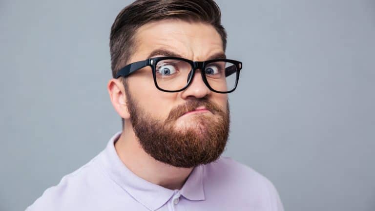 Portrait of a funny hipster man looking at camera over gray background