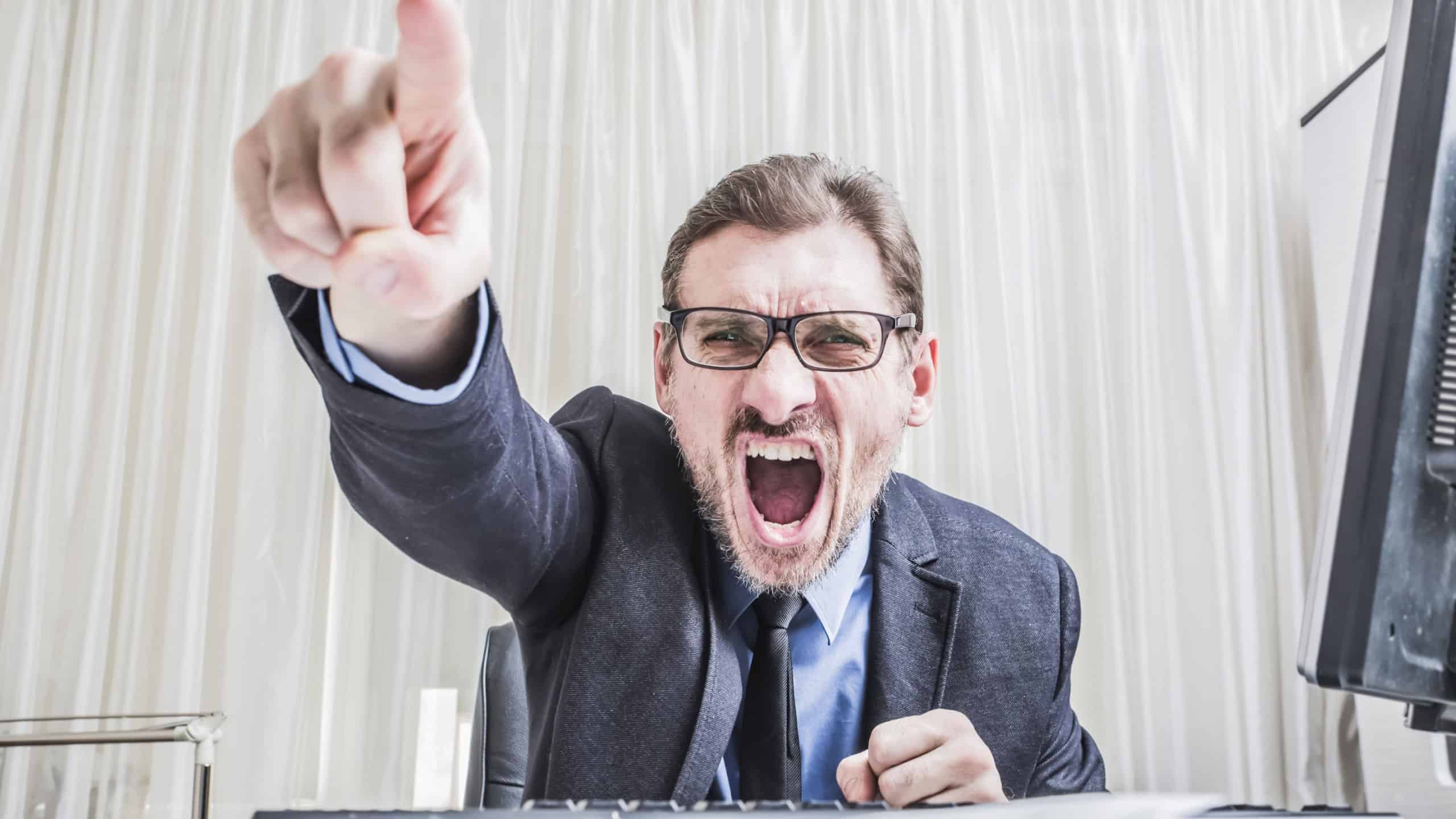 angry senior businessman sitting at his desk and screaming held out your hand