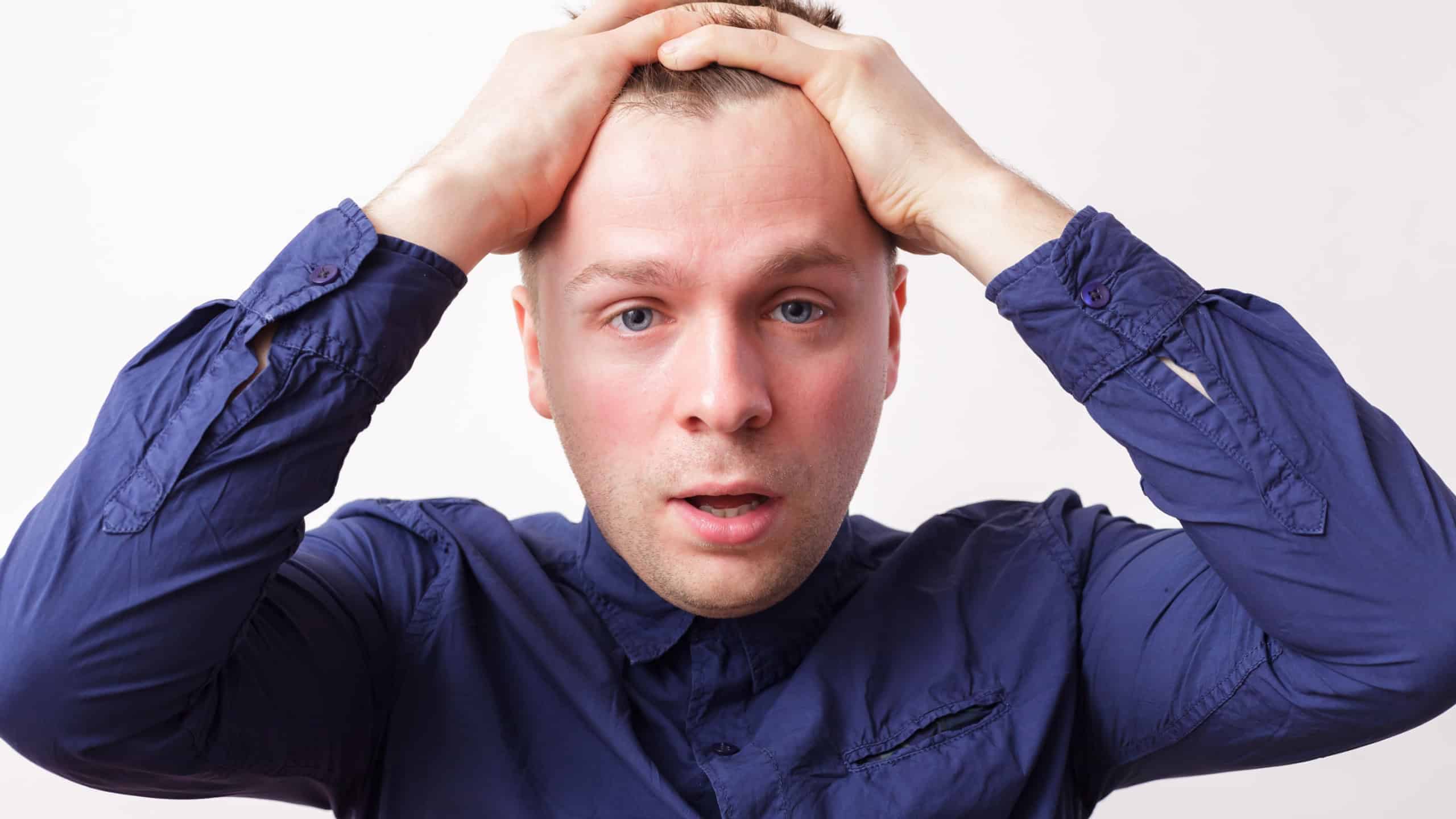 Young man in despair covers his head with  hands. Worry due to problems and stress