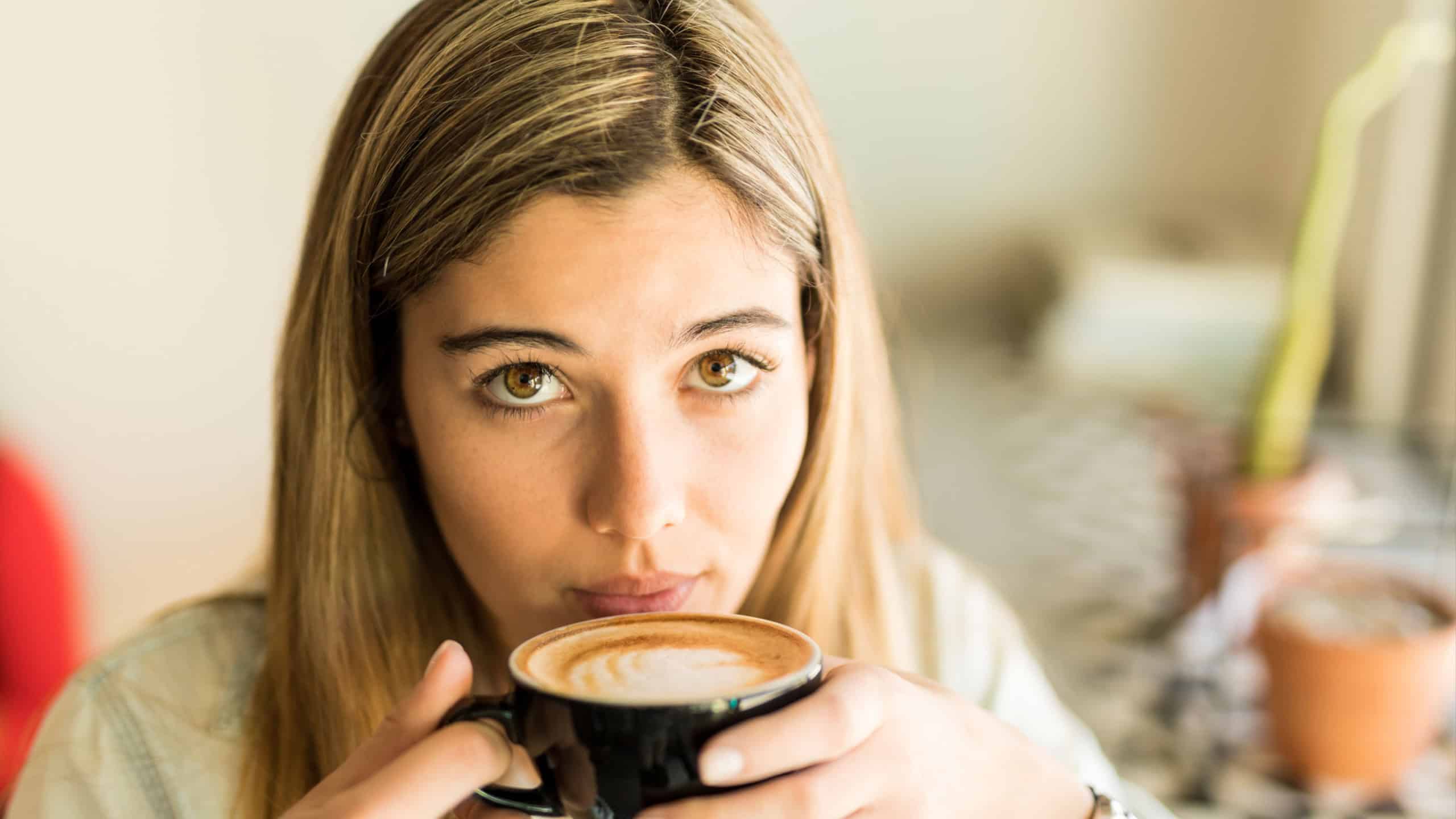 Gorgeous young woman drinking a cup of cappuccino in a coffee shop