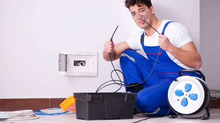 Funny young electrician working on socket at home